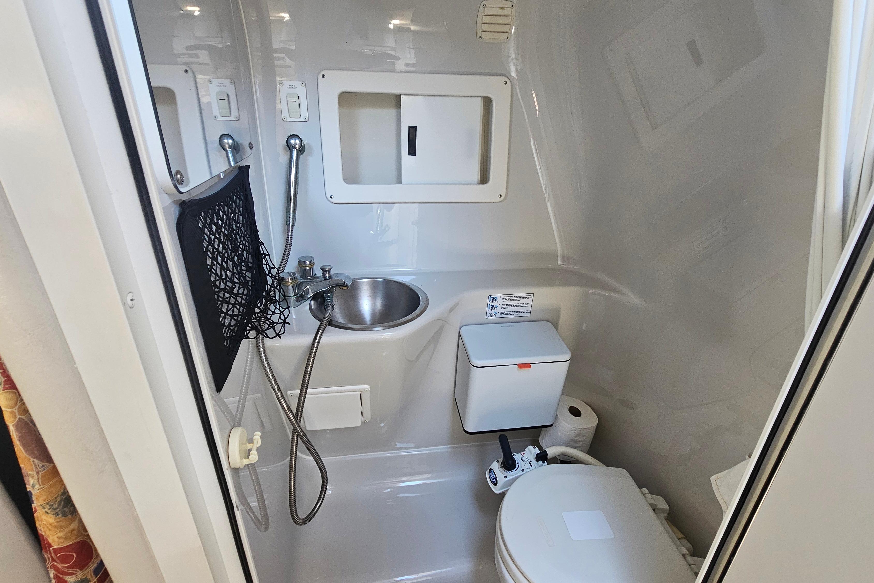 Compact bathroom in a 2000 Crownline 242 CR boat, featuring a sink and toilet.