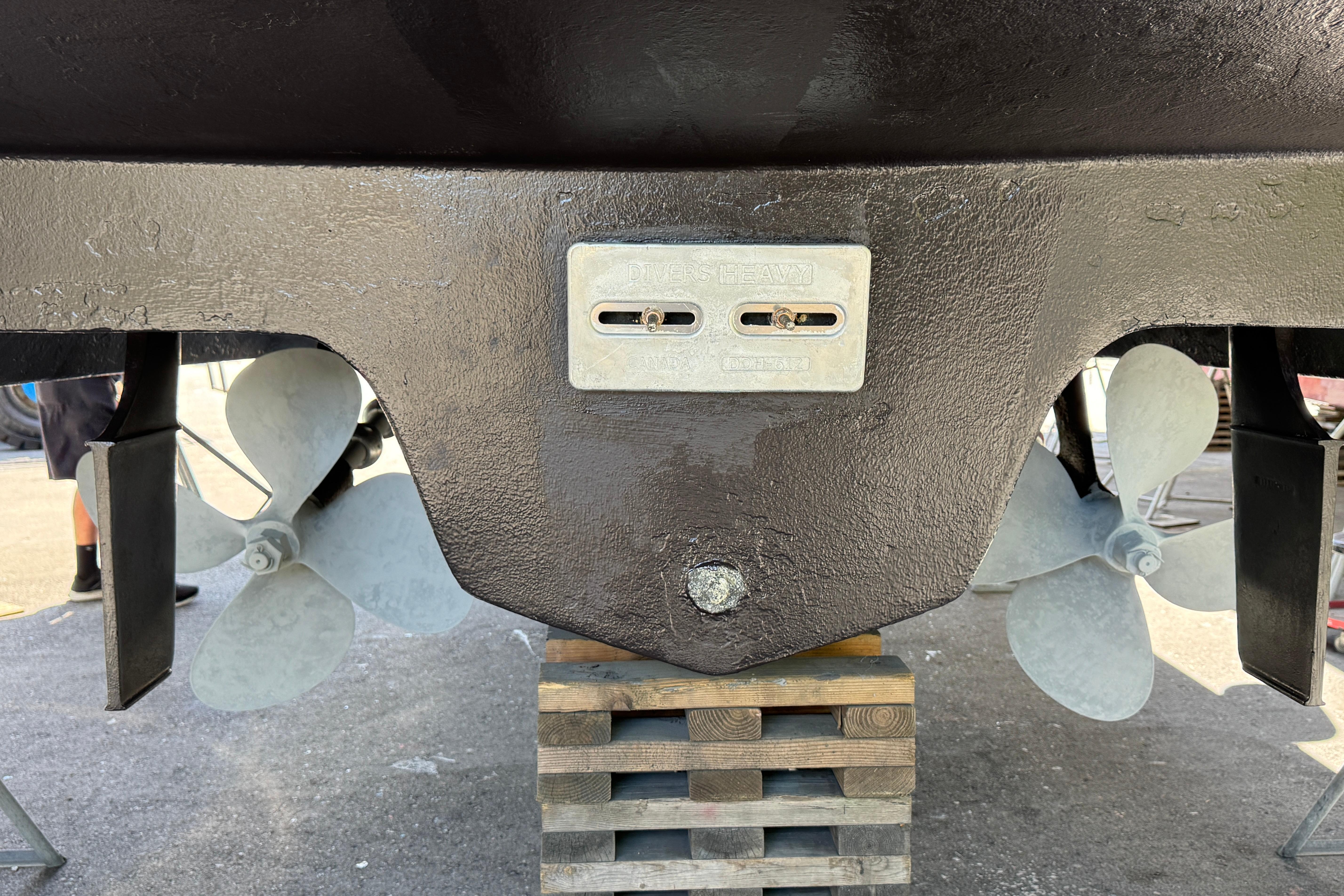 Propellers and hull of a 2000 Sea Ray 380 Aft Cabin boat on blocks.