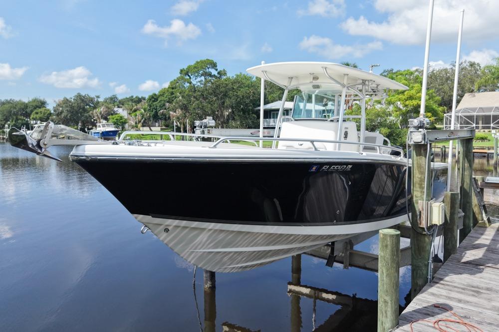 2018 Mako 284 Center Console boat docked on a lift by a serene waterfront.