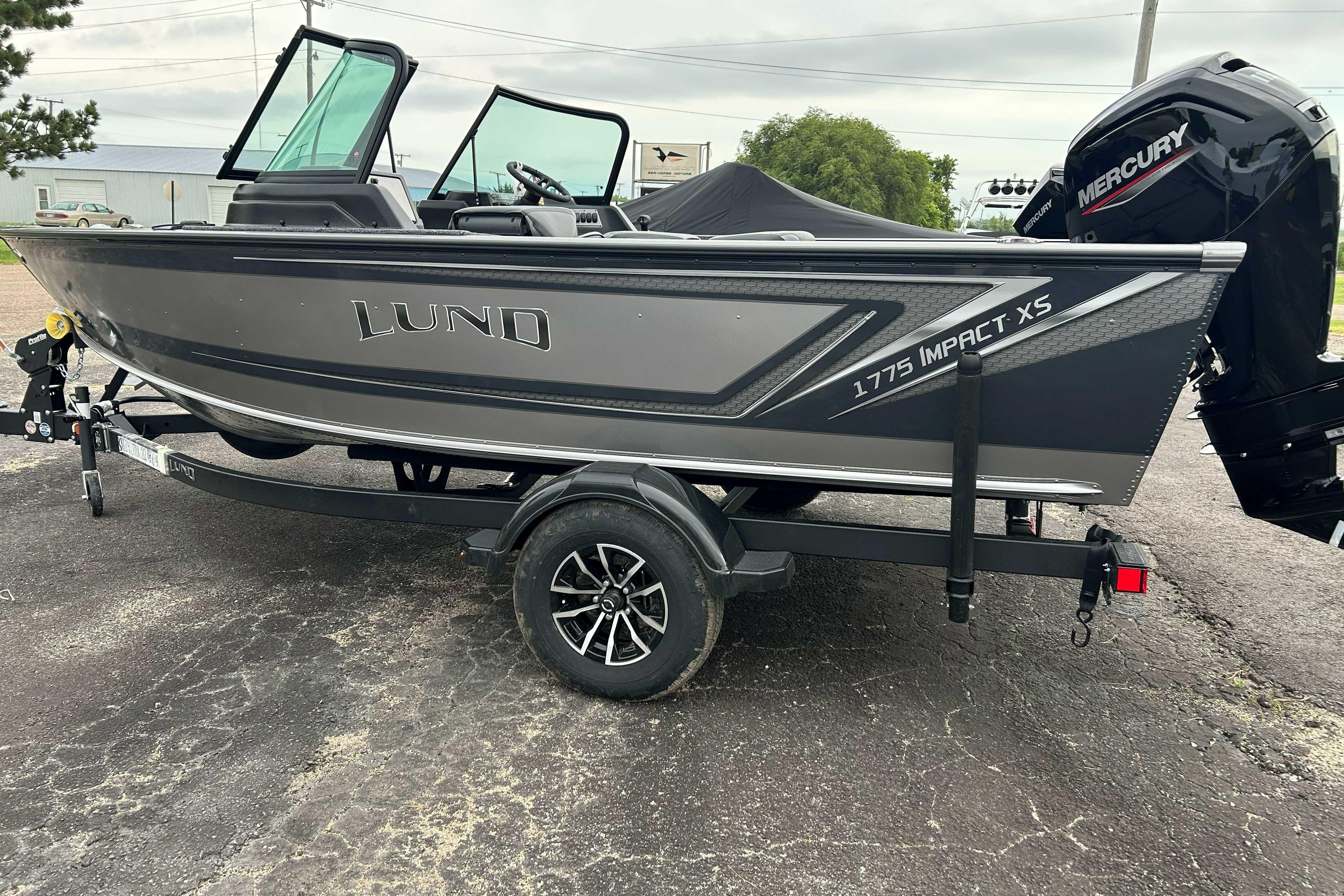 2027 Lund 1775 Impact XS boat on trailer with Mercury engine, parked outdoors.
