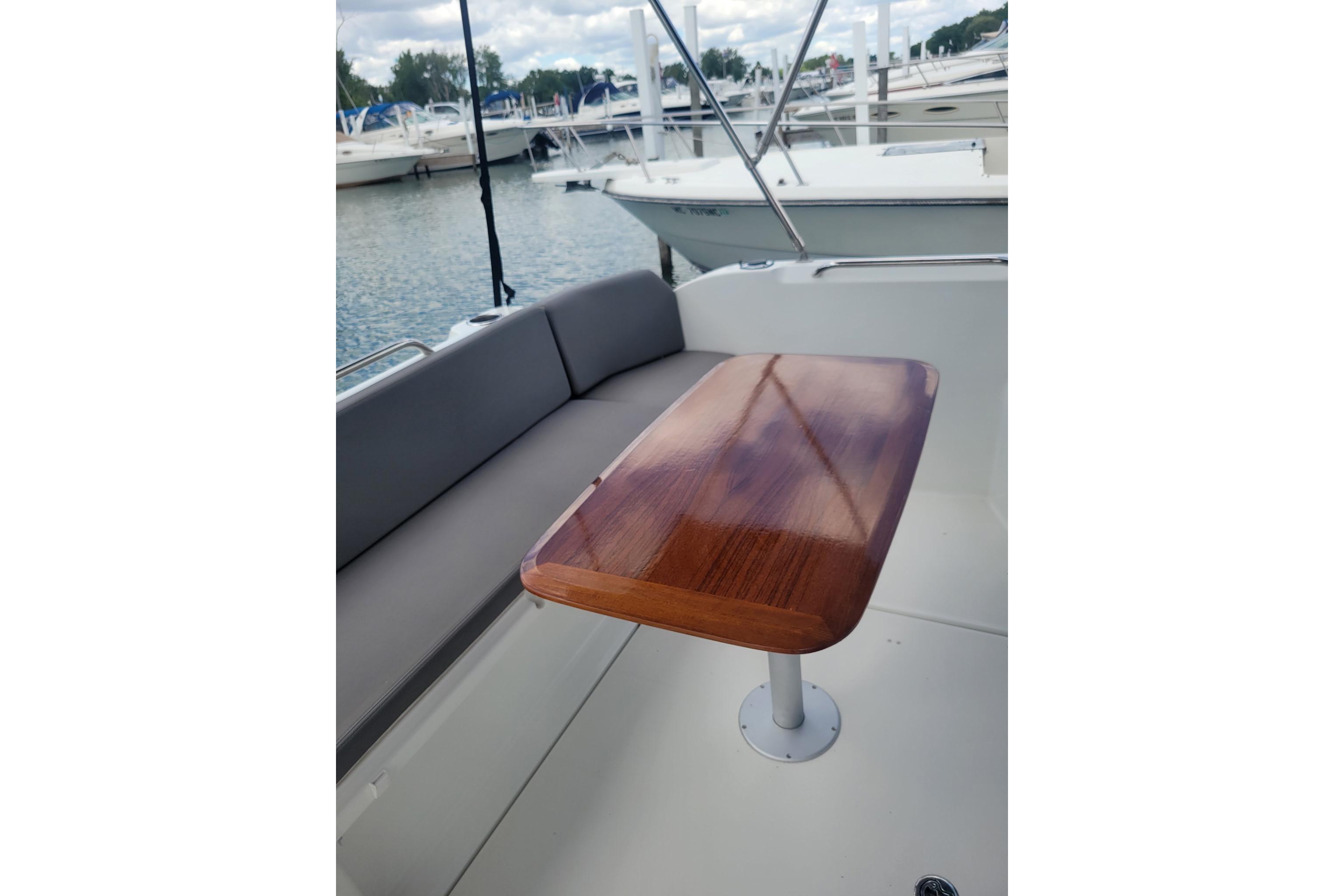 2019 Beneteau Antares 23 boat interior with wooden table and cushioned seating.