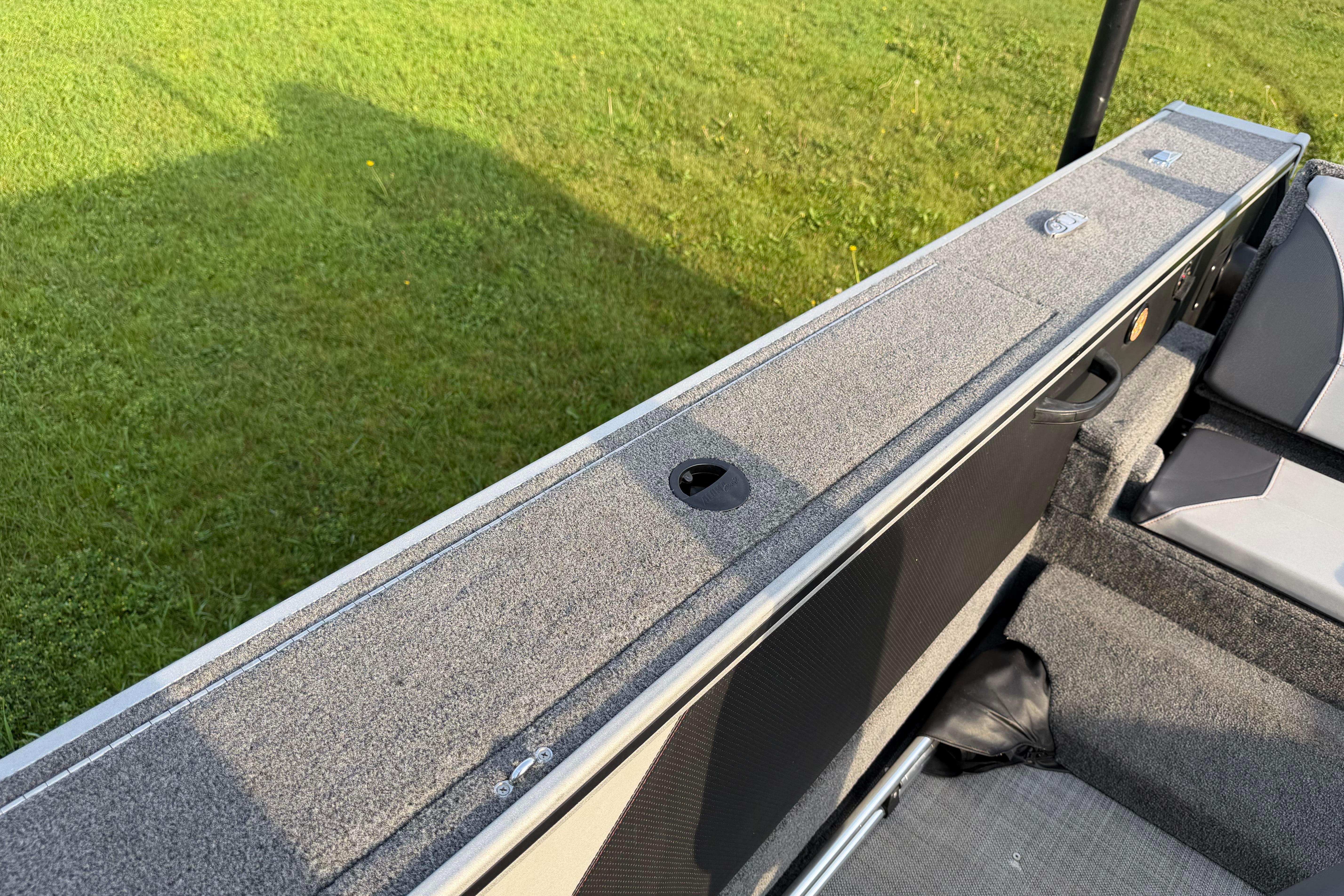 2019 Alumacraft Trophy 205 boat interior with gray carpet and seating, on grassy background.