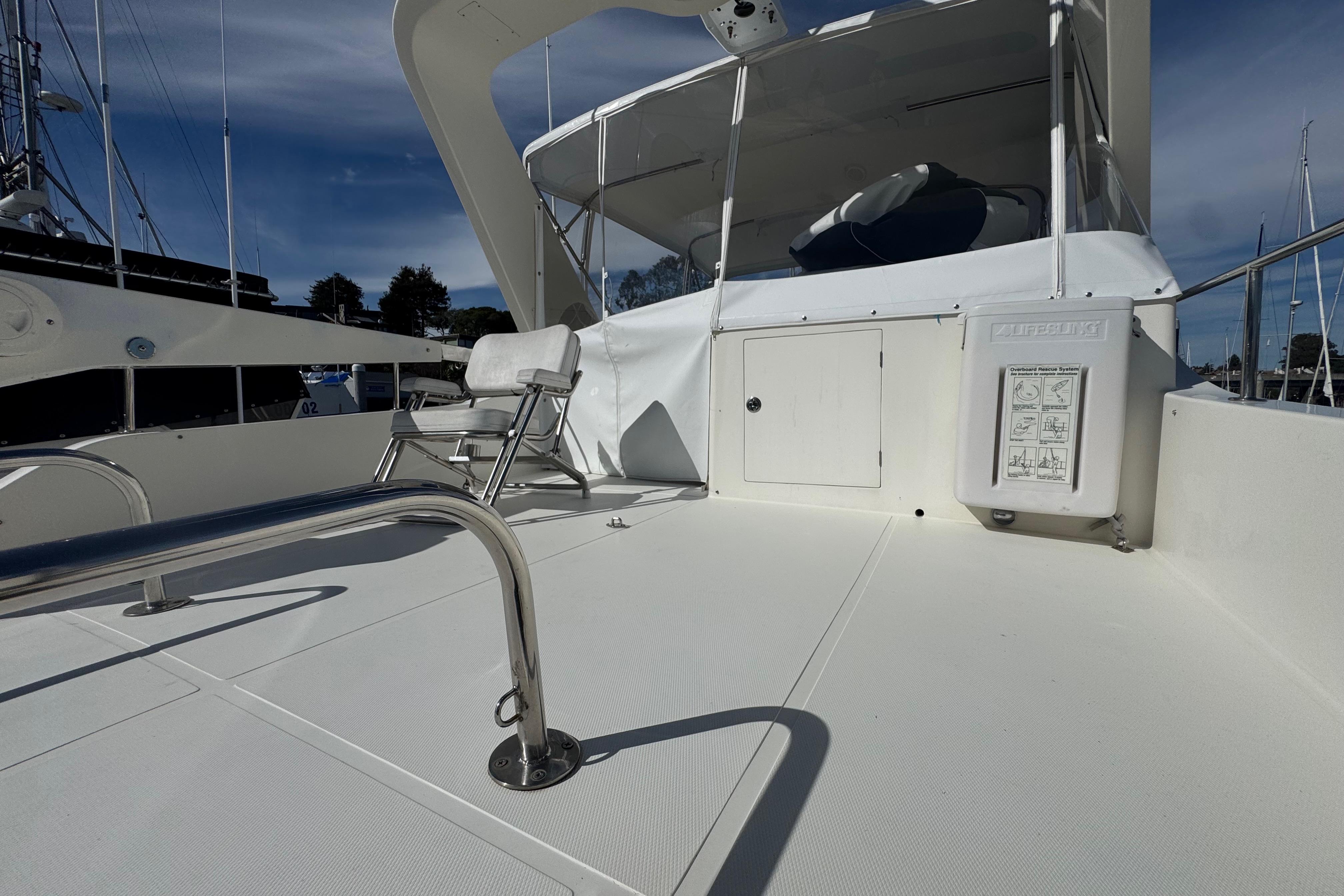 2002 Hampton 550 yacht deck with seating and safety equipment under clear skies.