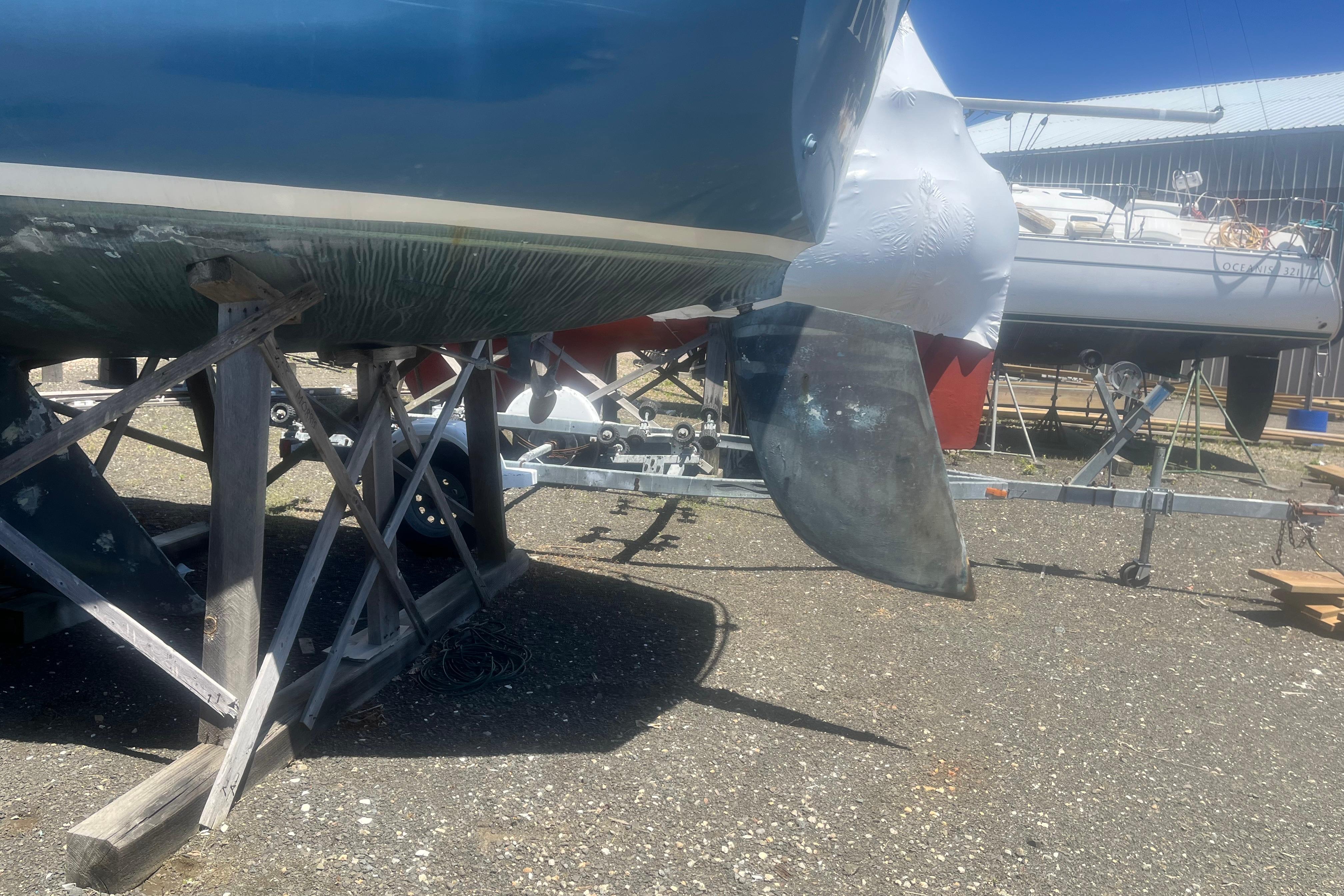 1972 C&C 30 sailboat on stands, showing hull and rudder in a boatyard.