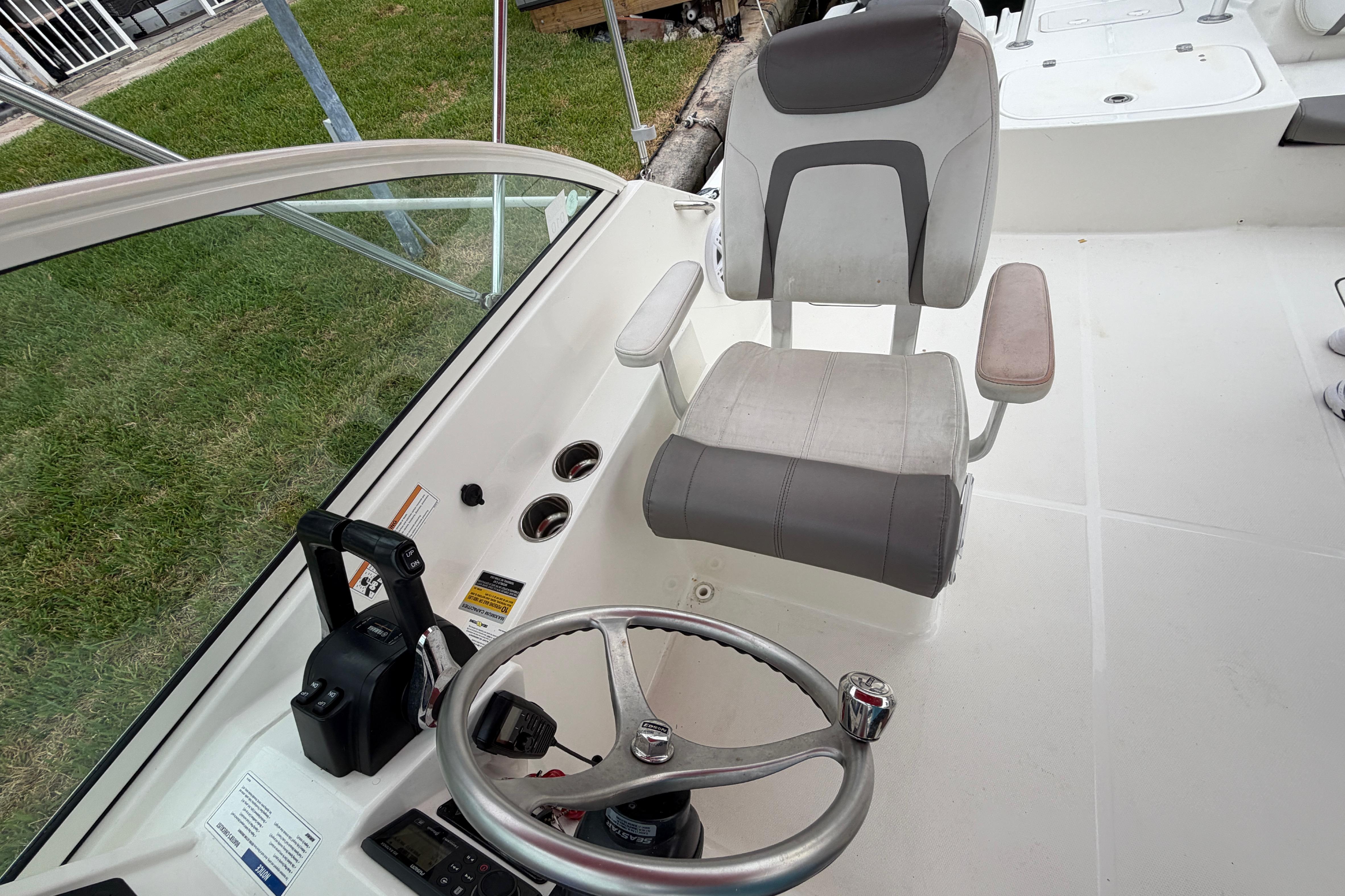 2019 World Cat 230 DC boat cockpit with steering wheel and captain's chair.