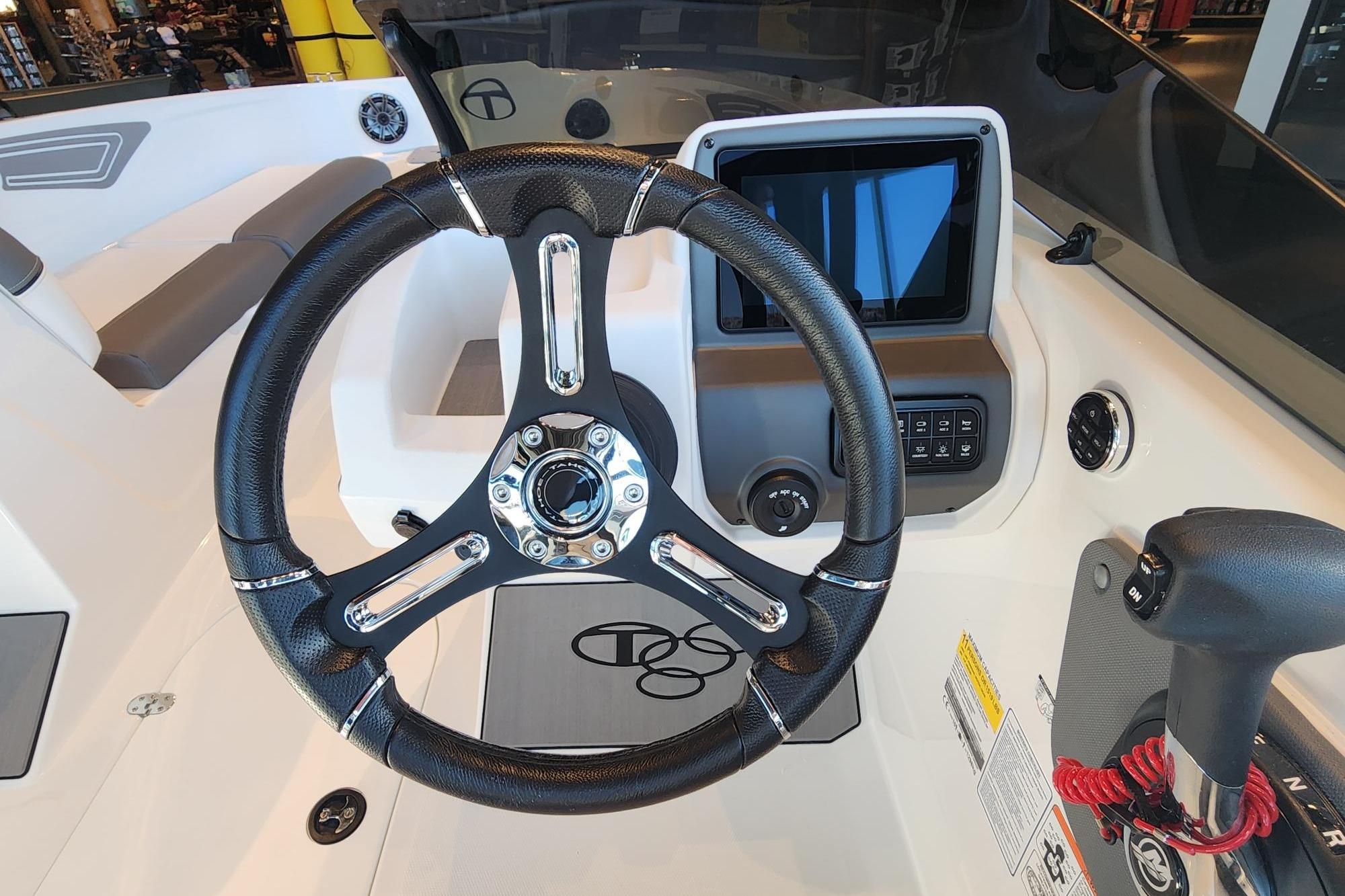 Steering wheel and dashboard of 2026 Tahoe T21 boat, featuring modern controls and display.