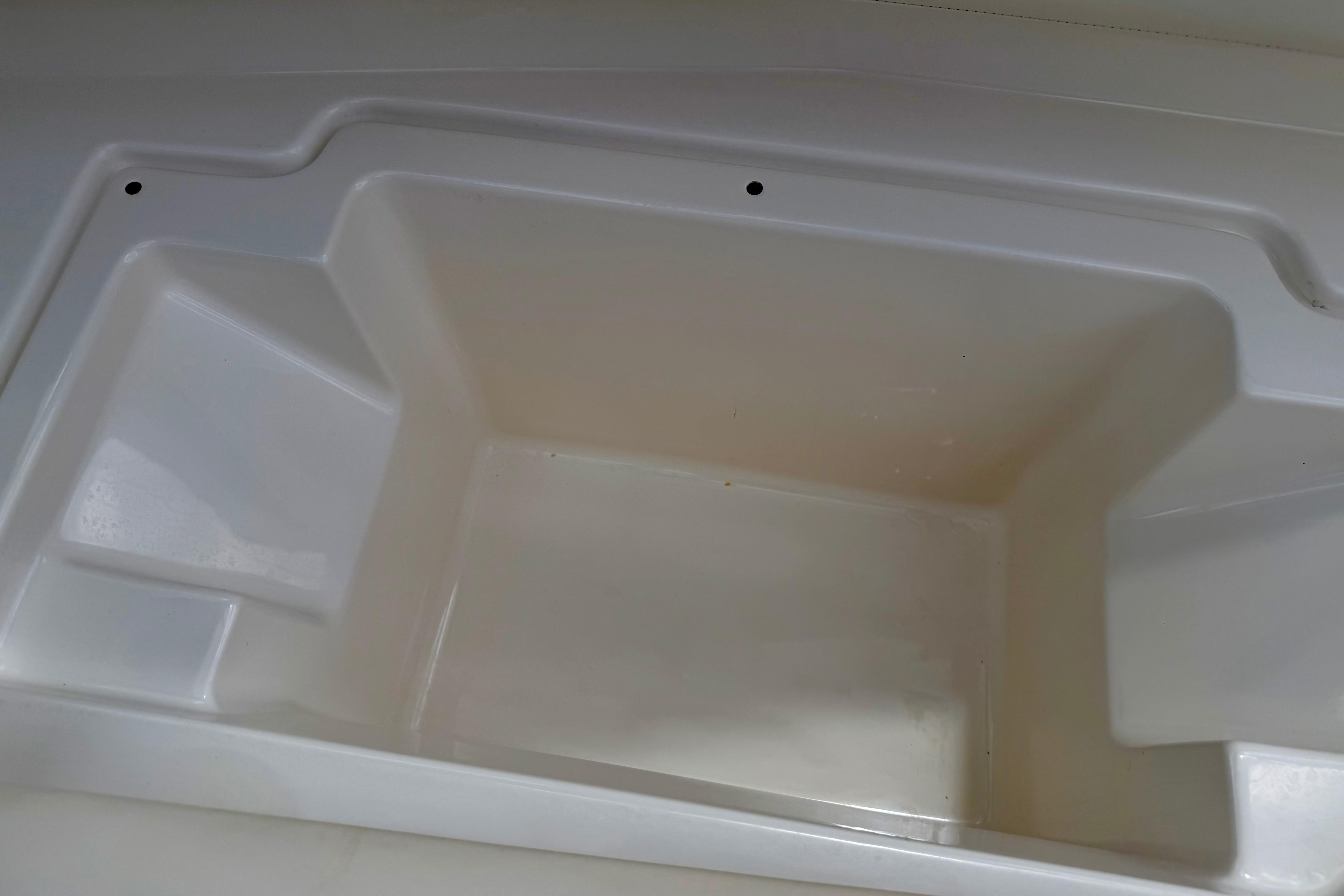 Storage compartment of a 2015 Chaparral Sunesta 264 boat, featuring a clean, white interior.