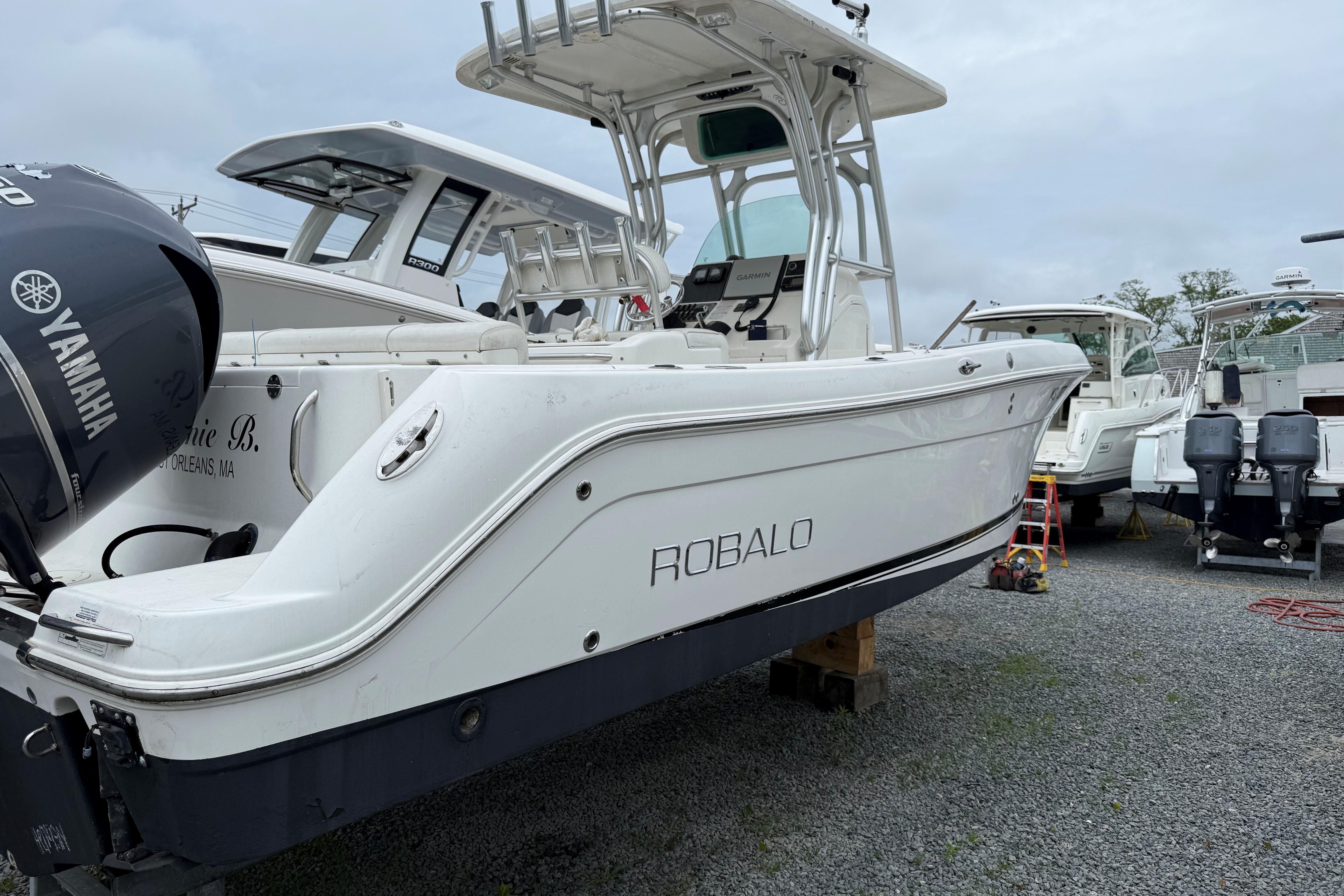 2009 Robalo R240 Center Console boat with Yamaha engine, parked on gravel lot.