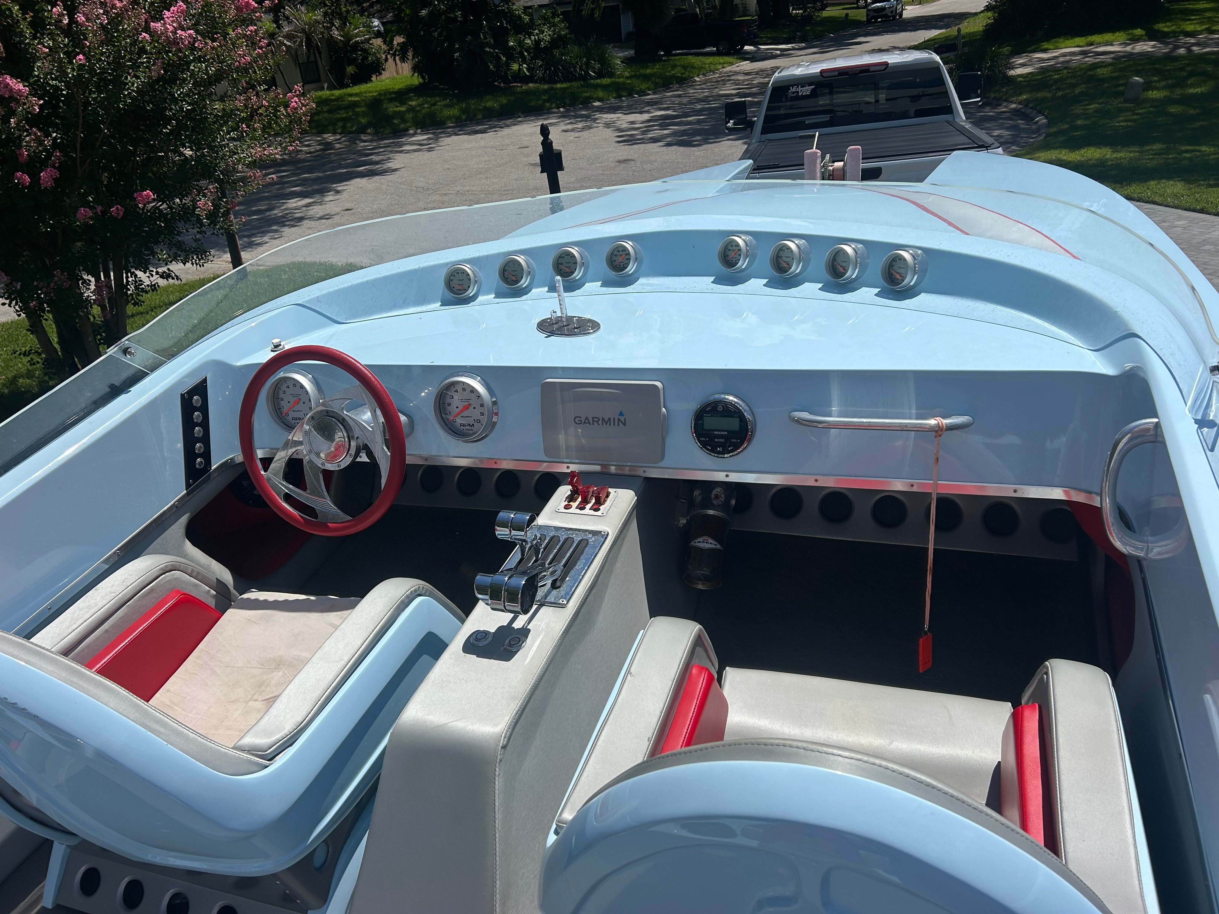 The cockpit of a blue motorboat with red accents and a Garmin display.