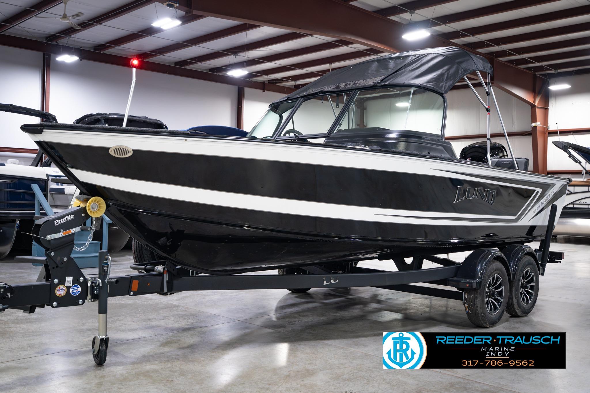 2026 Lund 1875 Impact XS SS boat in showroom, black and white design, on trailer.