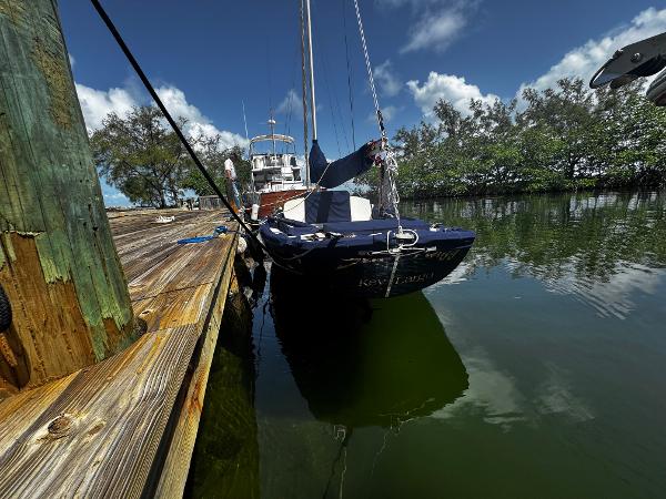 1968 Sailboat 24 docked on calm water under a clear blue sky.