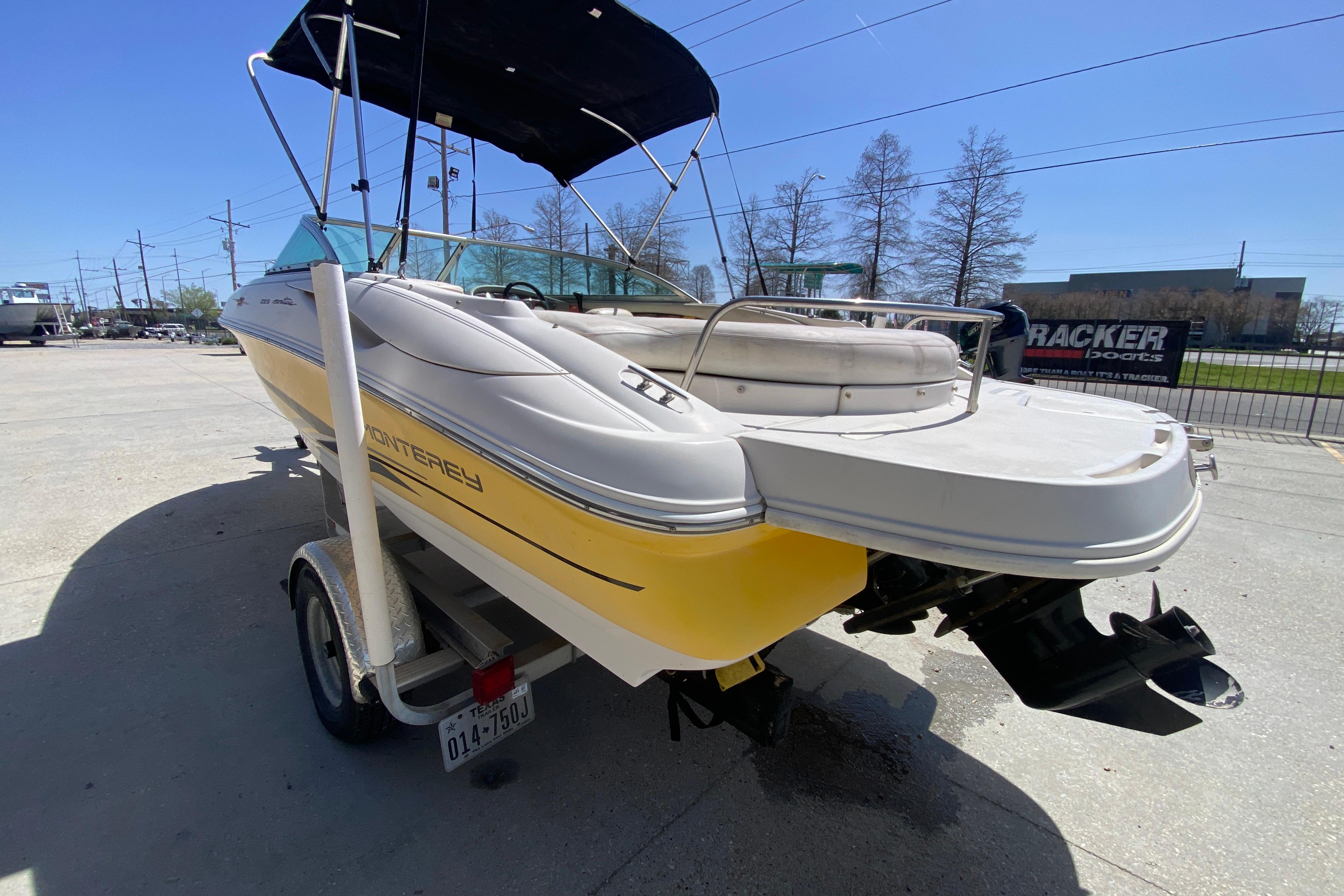 2003 Monterey 208SI Montura boat on trailer, yellow and white, parked outdoors.