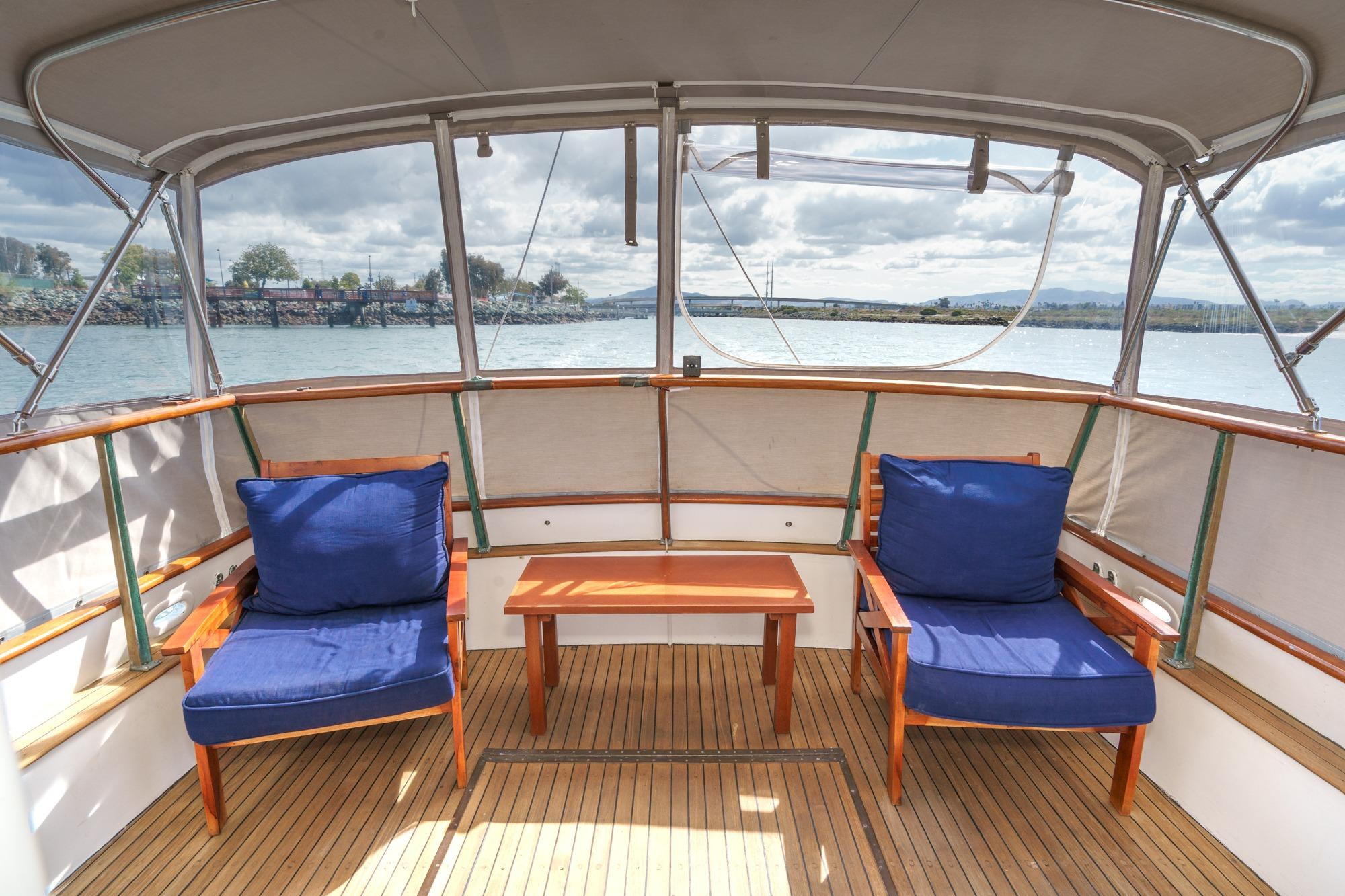 1966 Grand Banks 32 Sedan boat deck with blue cushioned chairs and wooden table.