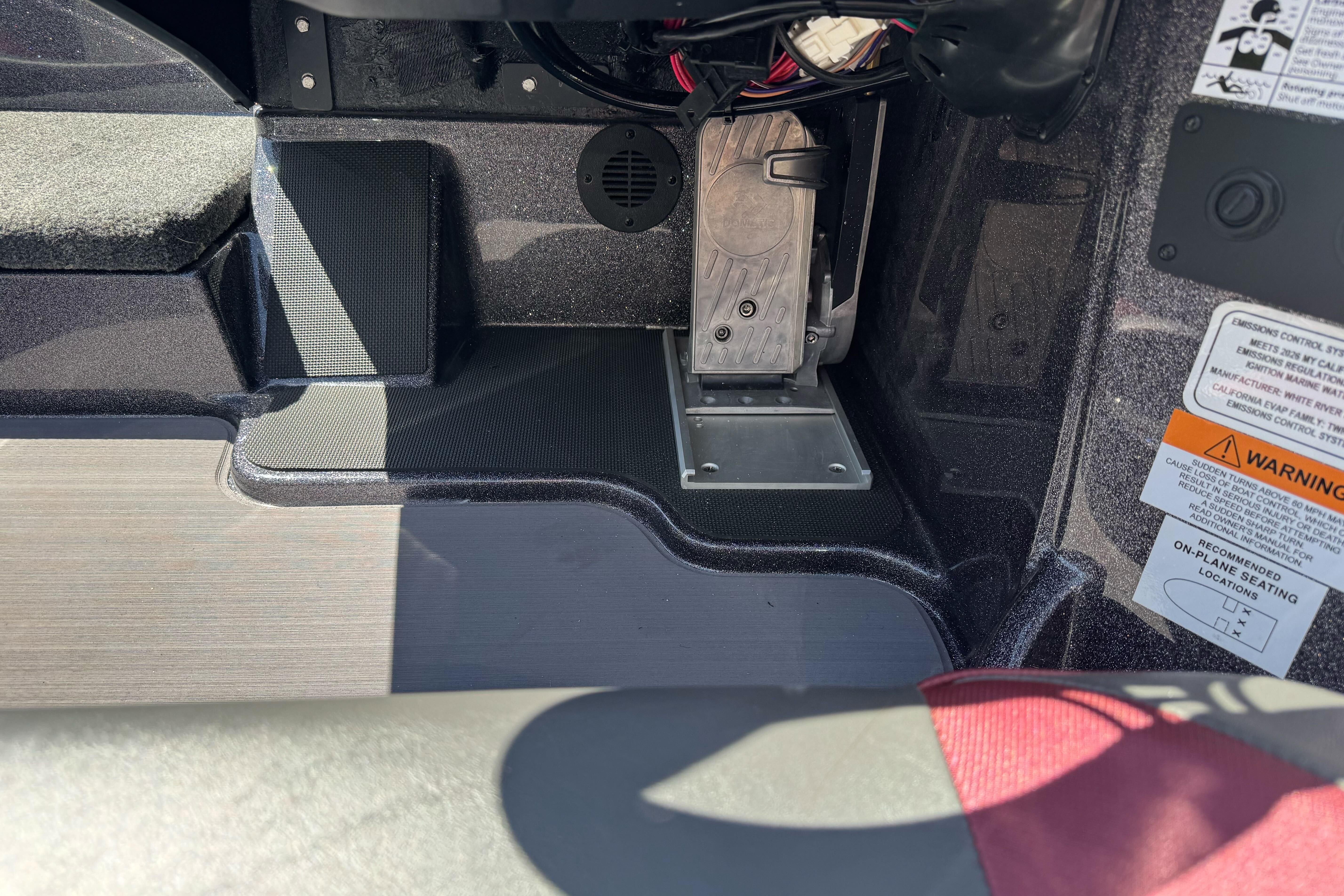 Interior view of a 2026 Triton 18 TrX boat, showcasing foot pedal and warning labels.