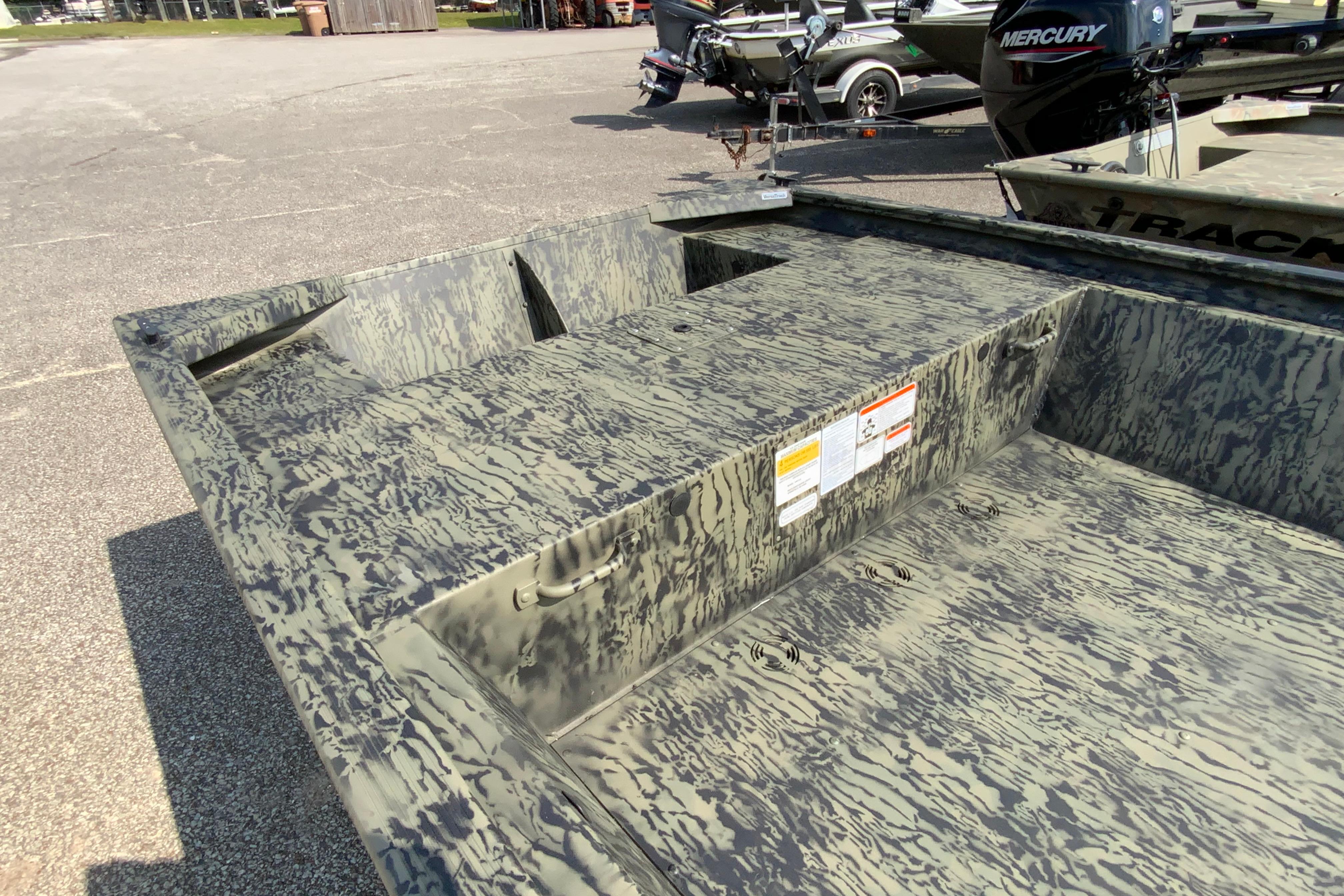 2026 Tracker Grizzly 1648 Utility boat with camouflage pattern, parked outdoors.
