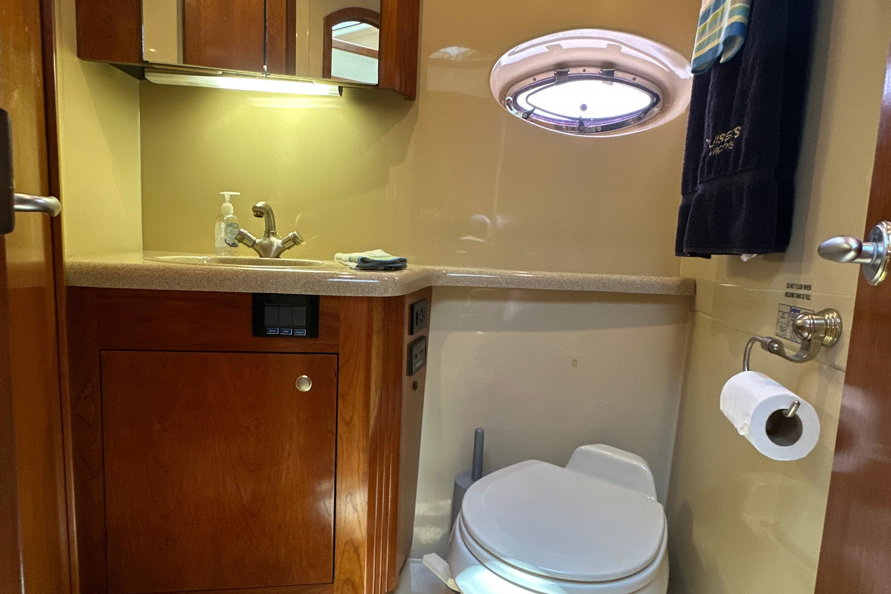 2004 Cruisers Yachts 405 Express Motoryacht bathroom with sink, toilet, and porthole window.