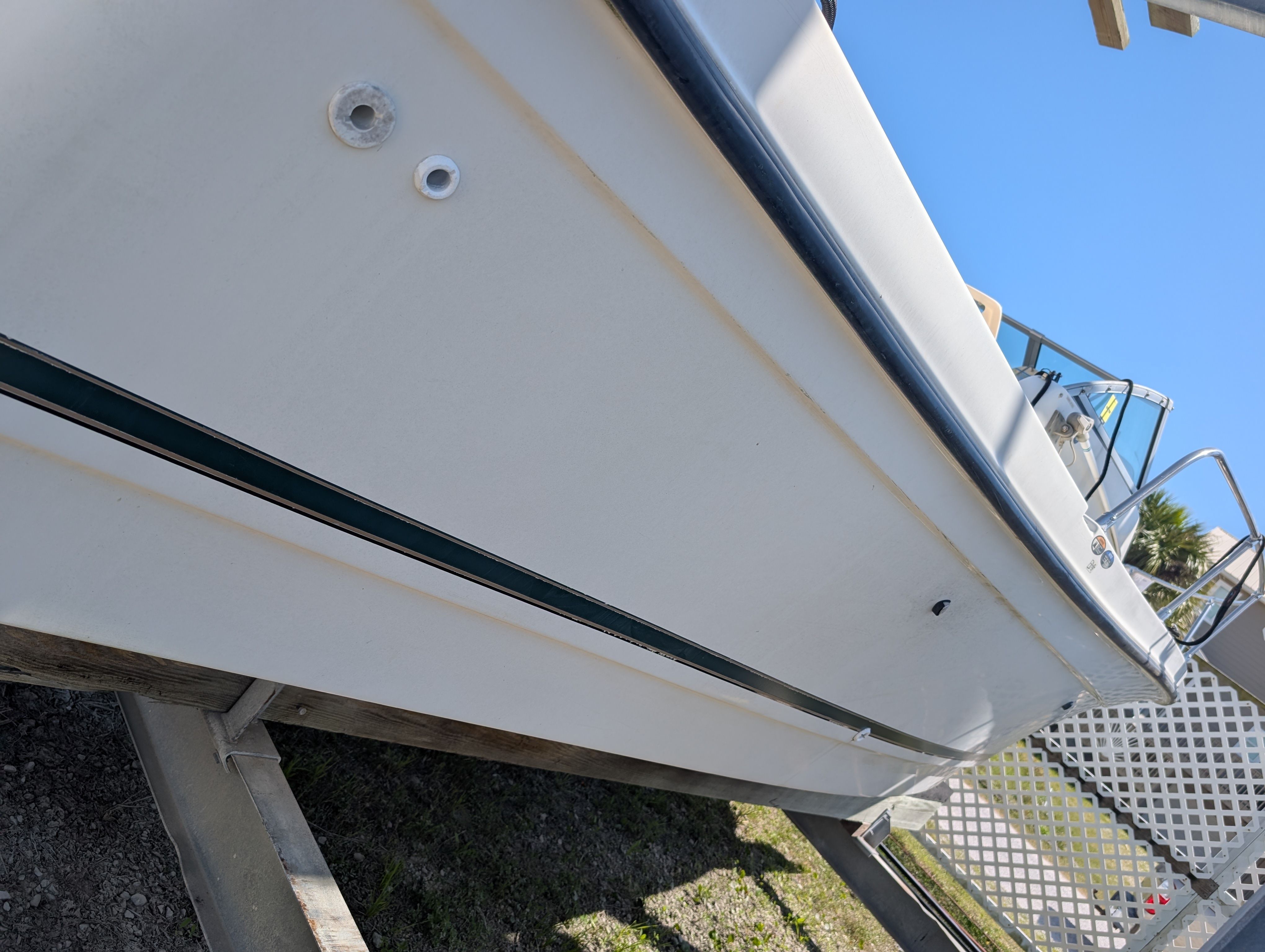 A white boat, likely a 2001 Trophy Bayliner, is on a trailer. The sky is clear.