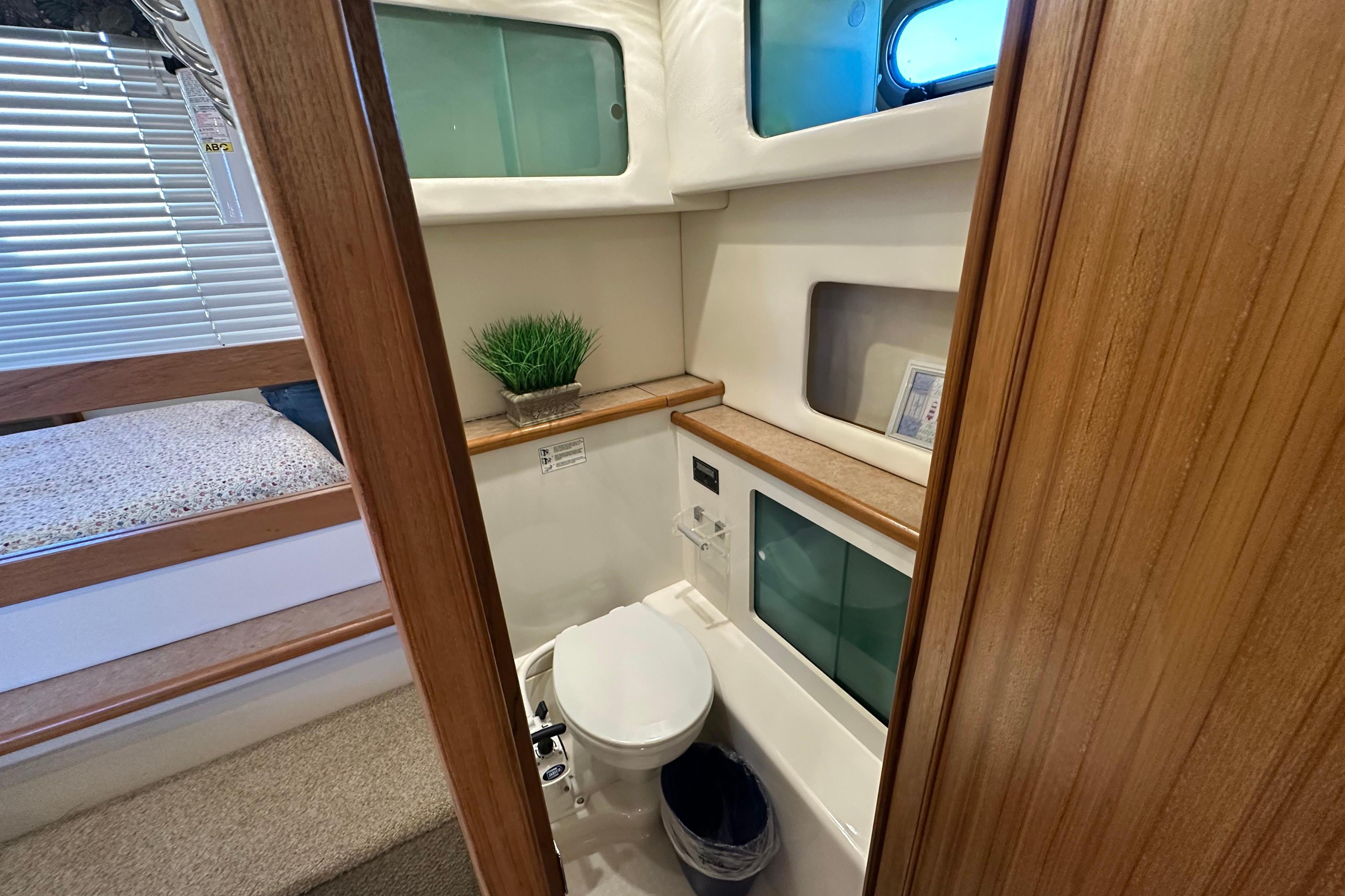 Bayliner 4087 Aft Cabin Motoryacht 2000 bathroom with toilet, storage, and porthole window.