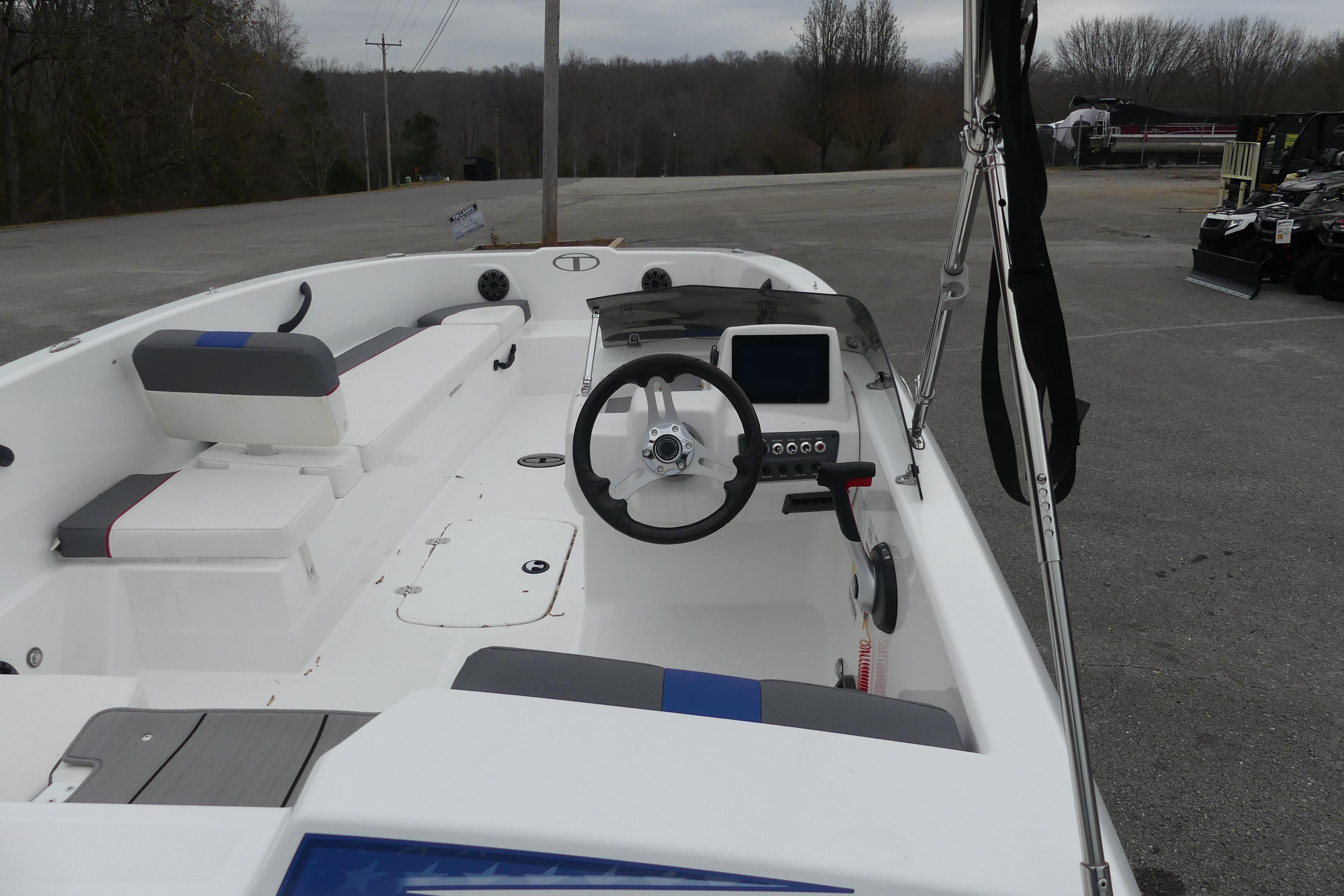 2024 Tahoe T18 boat interior with steering wheel and seating, parked outdoors.