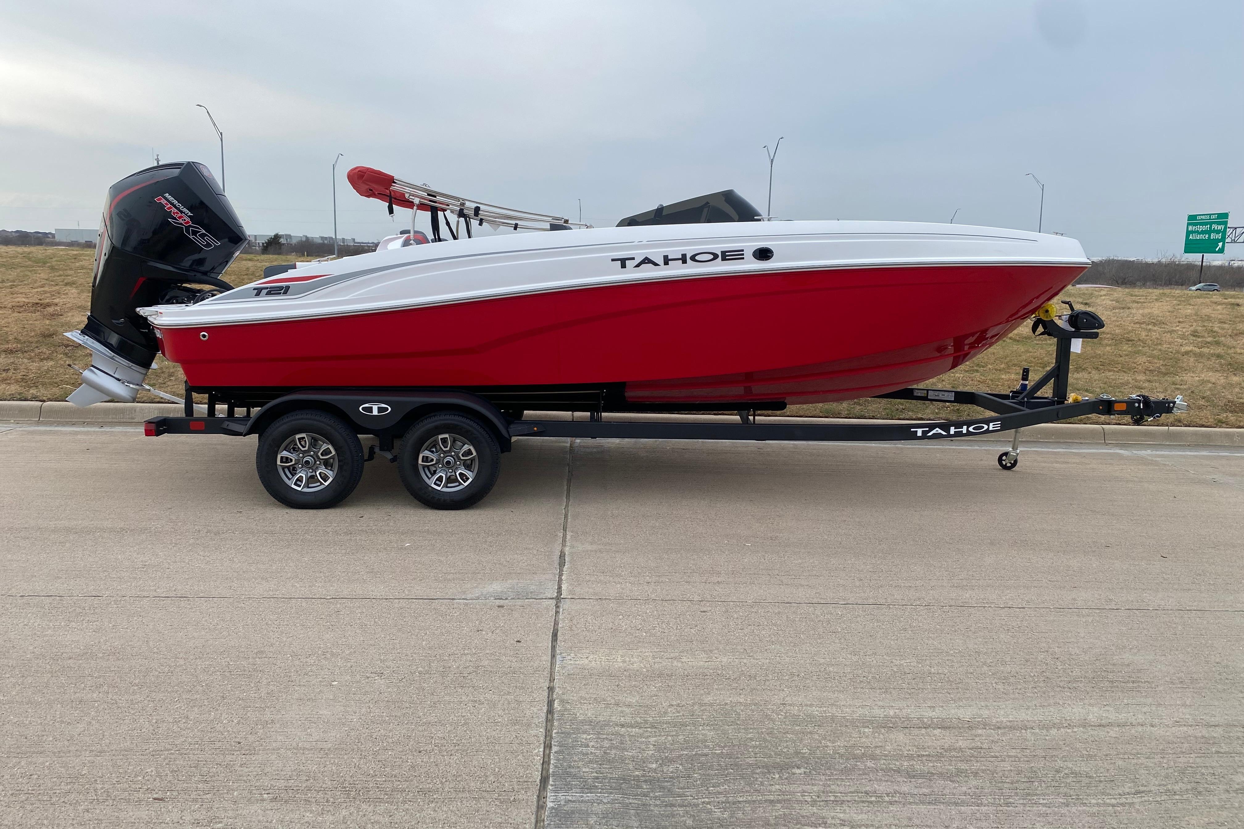 2026 Tahoe T21 boat on trailer, red and white design, parked outdoors.
