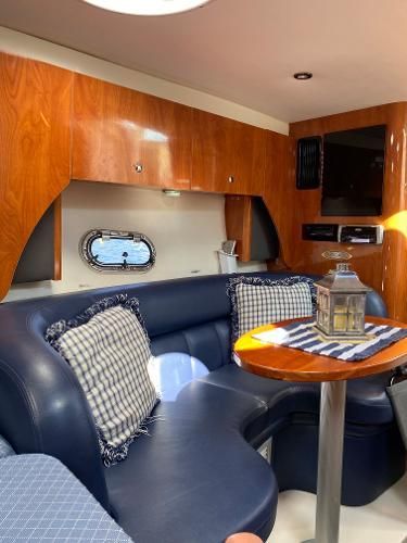 Interior of a yacht with blue leather seating and wooden cabinetry.