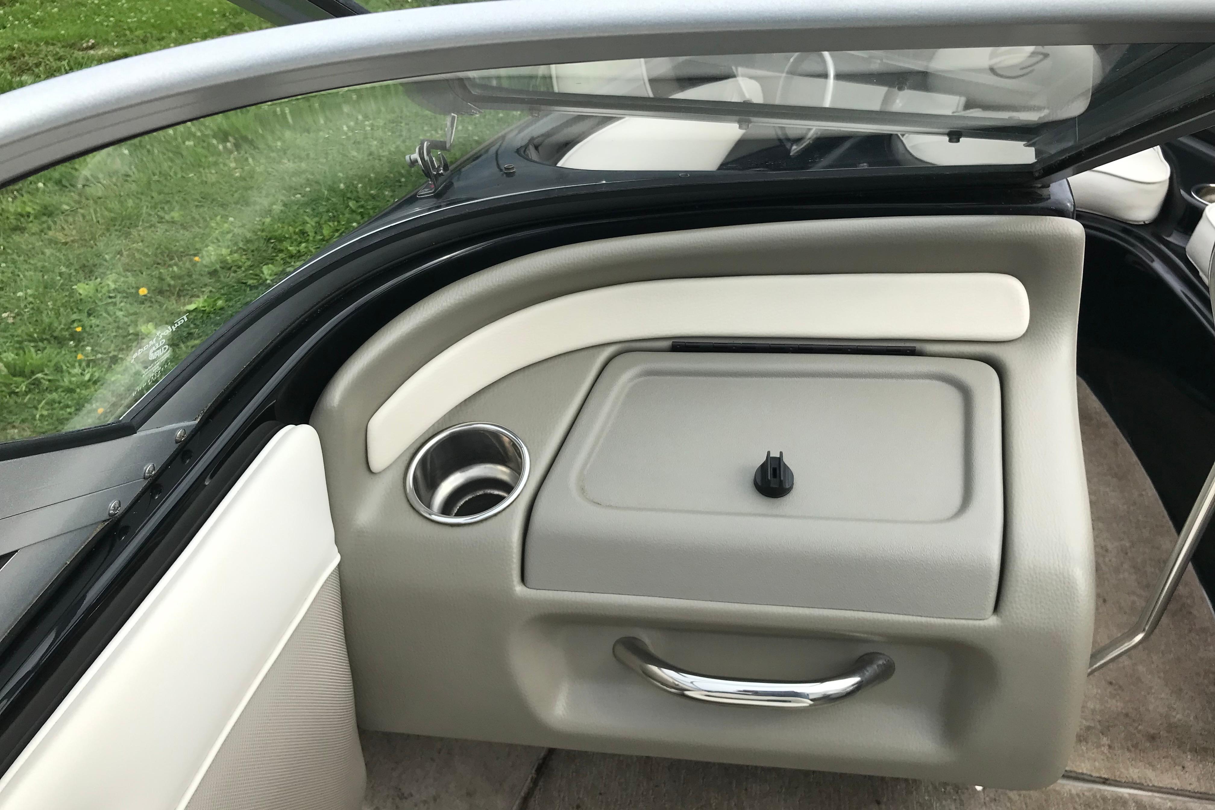 Interior view of a 2015 Crownline 18 SS boat, featuring a storage compartment and cup holder.