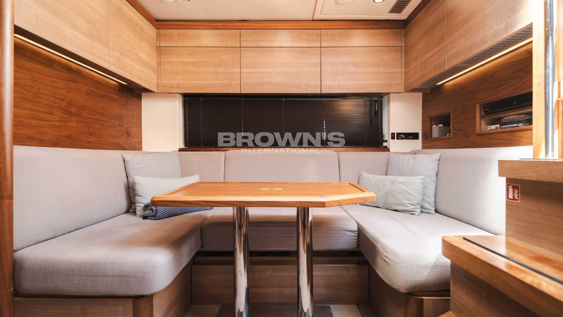 2012 Sealine SC42 yacht interior with cozy seating and wooden dining table.