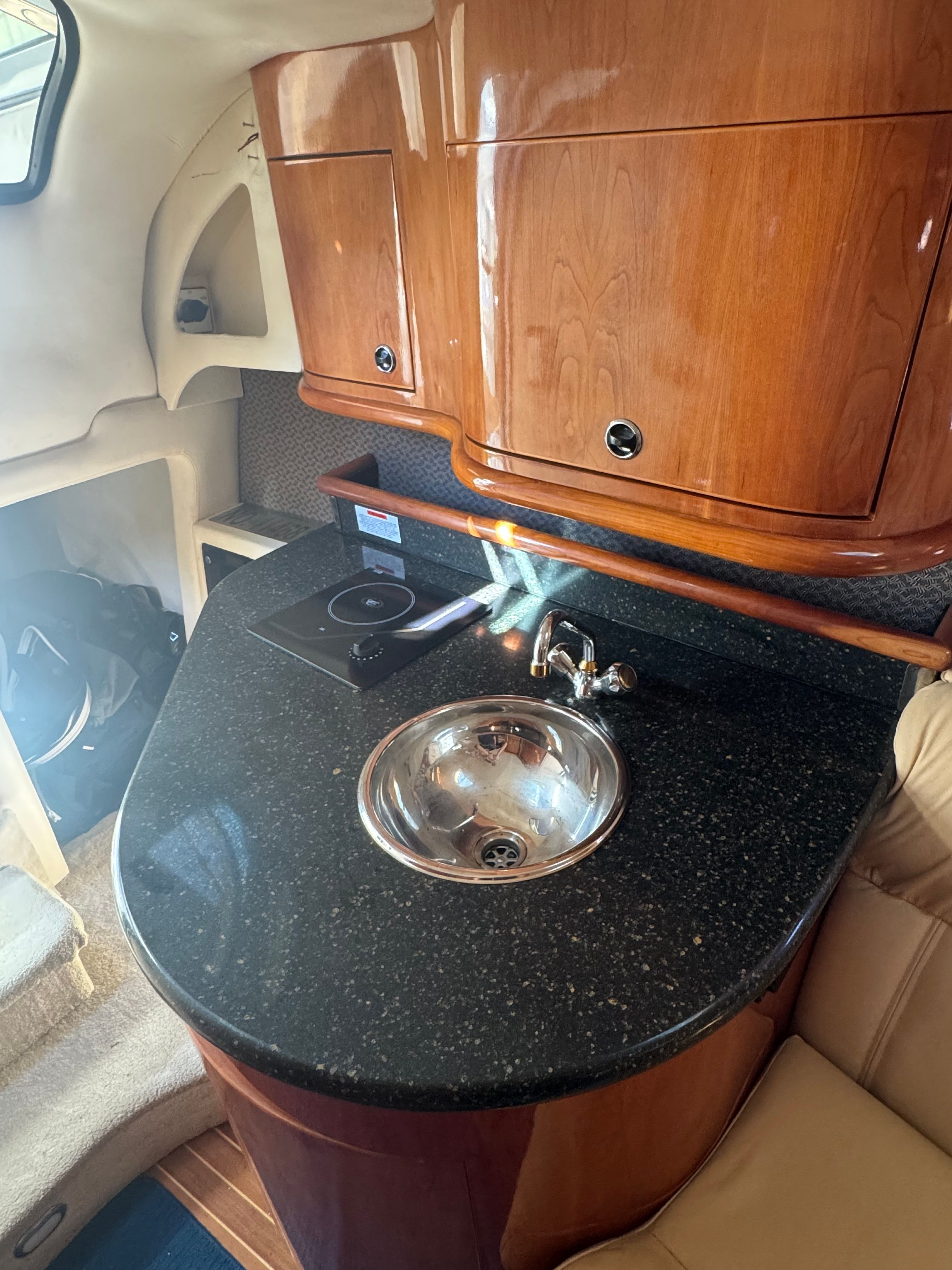 The interior view shows an elegant kitchenette with wooden cabinets and a round sink.