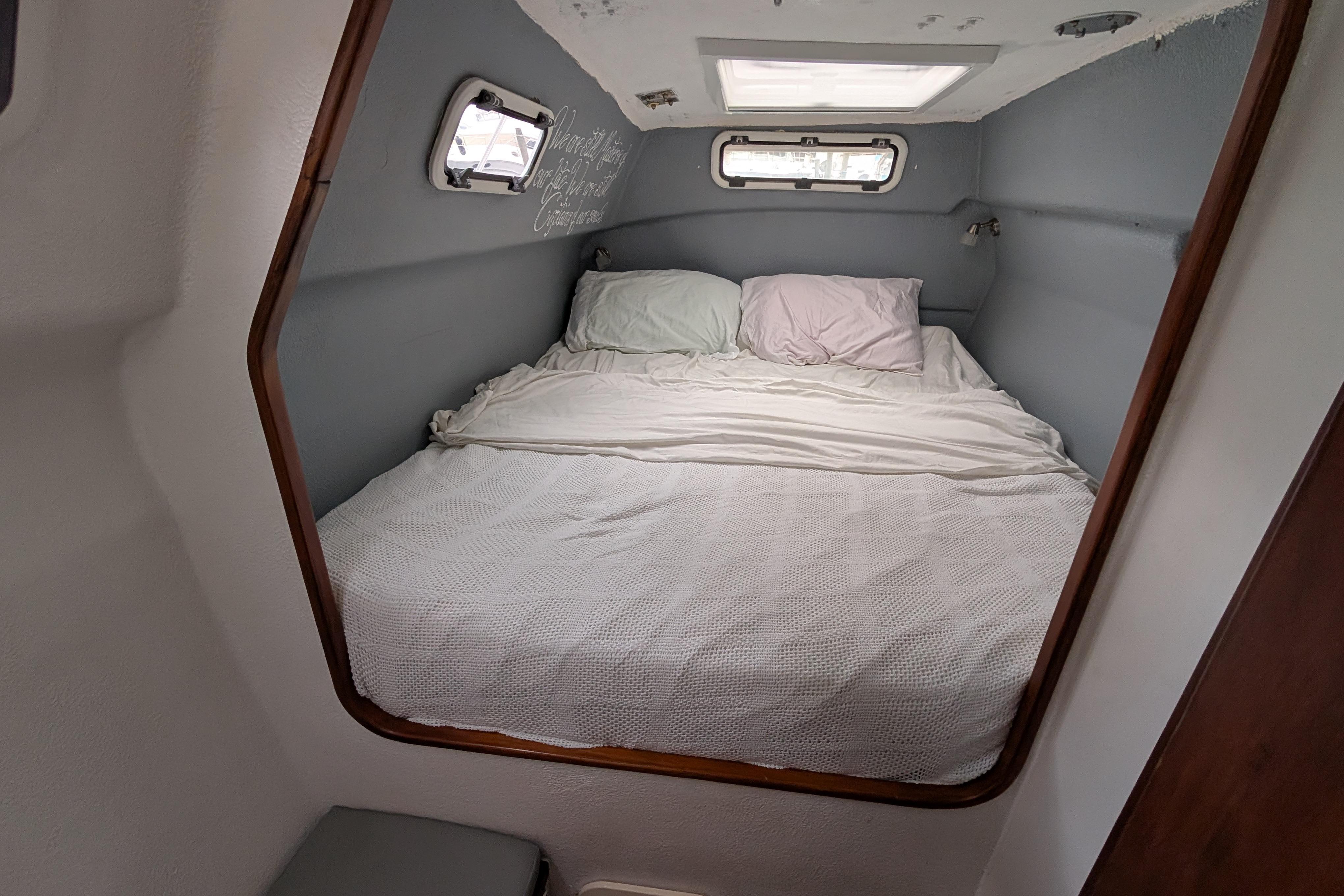 Cozy cabin bedroom in a 1999 Island Spirit 37 yacht with porthole windows.