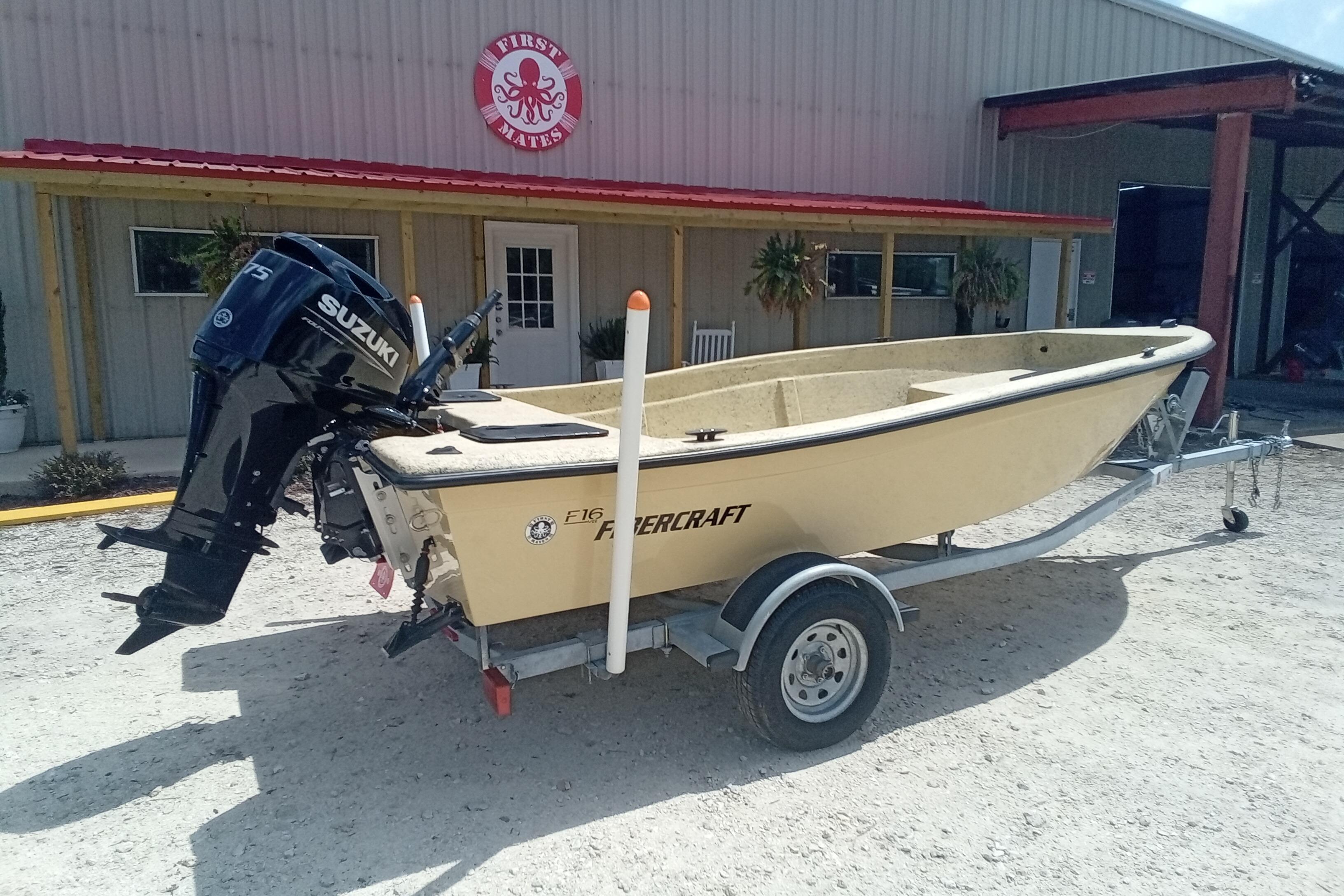 2025 Fibercraft F16 boat with Suzuki engine on trailer outside a building.