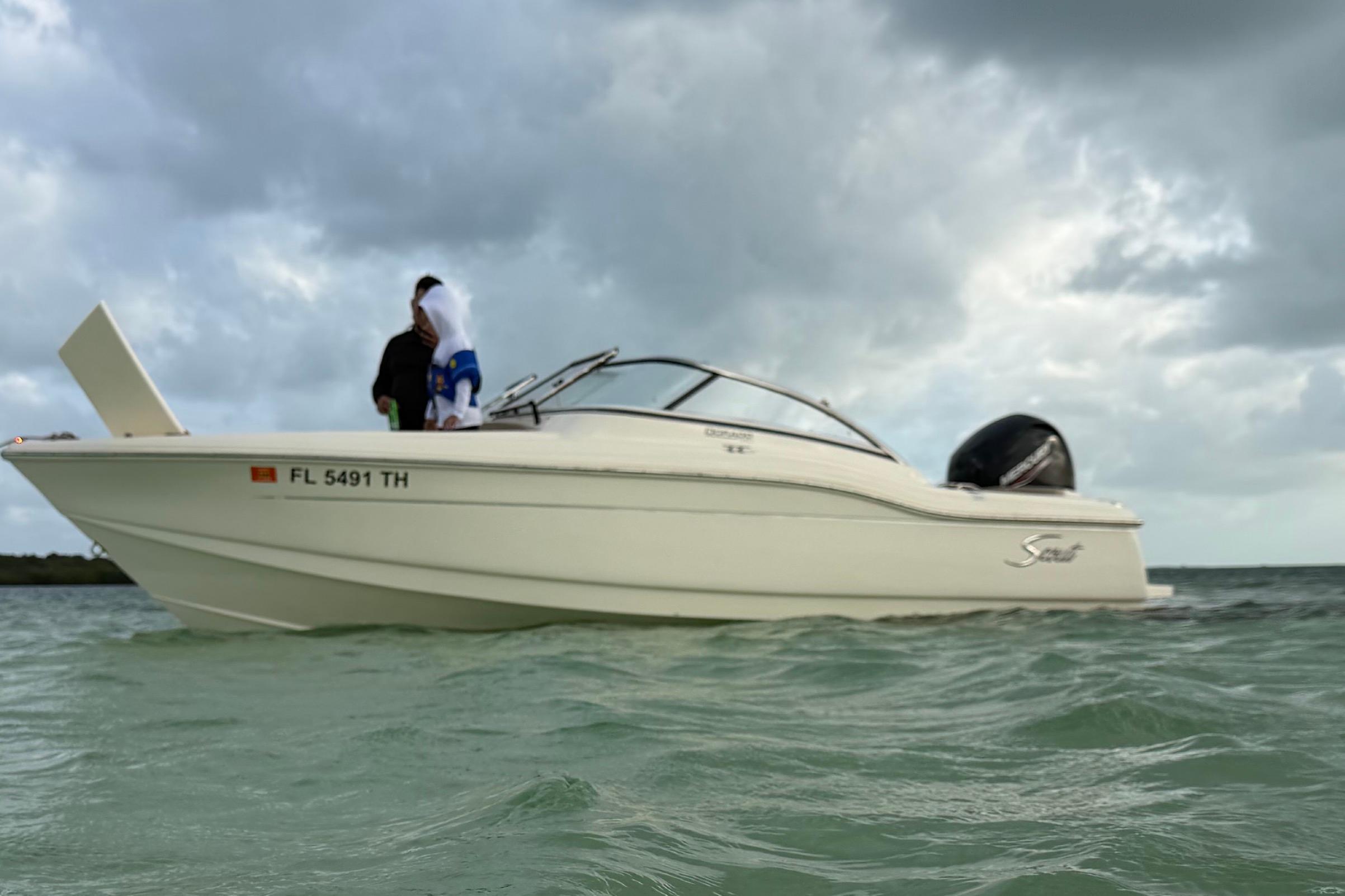 2023 Scout 210 Dorado boat on water under cloudy sky.