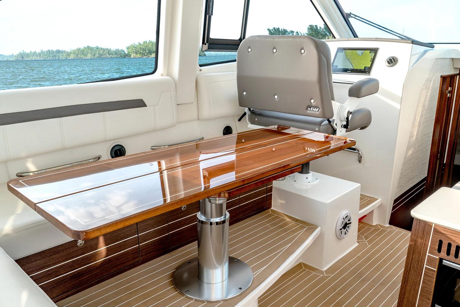 Manufacturer Provided Image: Luxurious interior of 2025 Pursuit OS 445 Offshore boat with polished wood table and seating.