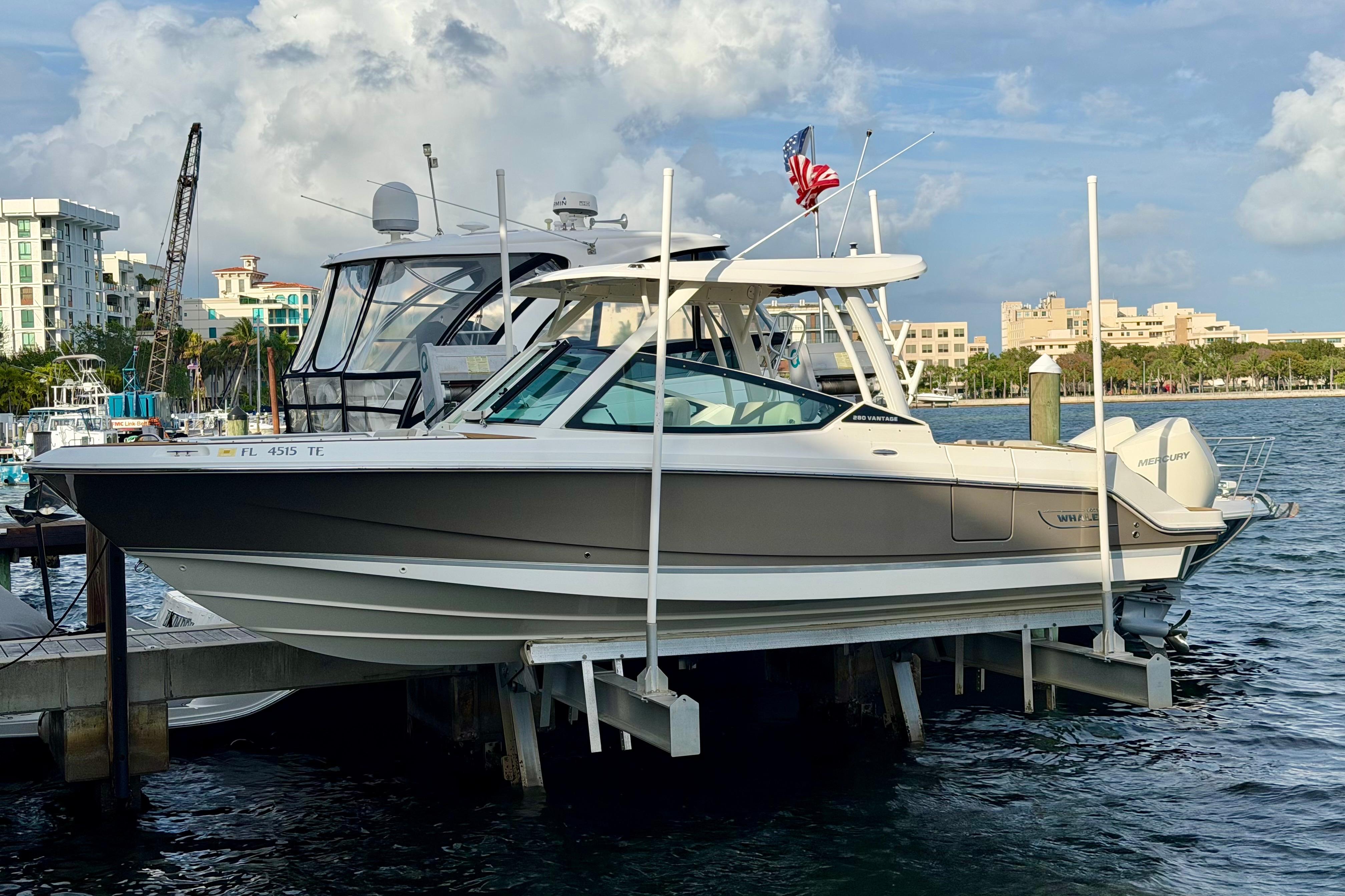 2022 Boston Whaler 280 Vantage boat docked at marina with cityscape background.