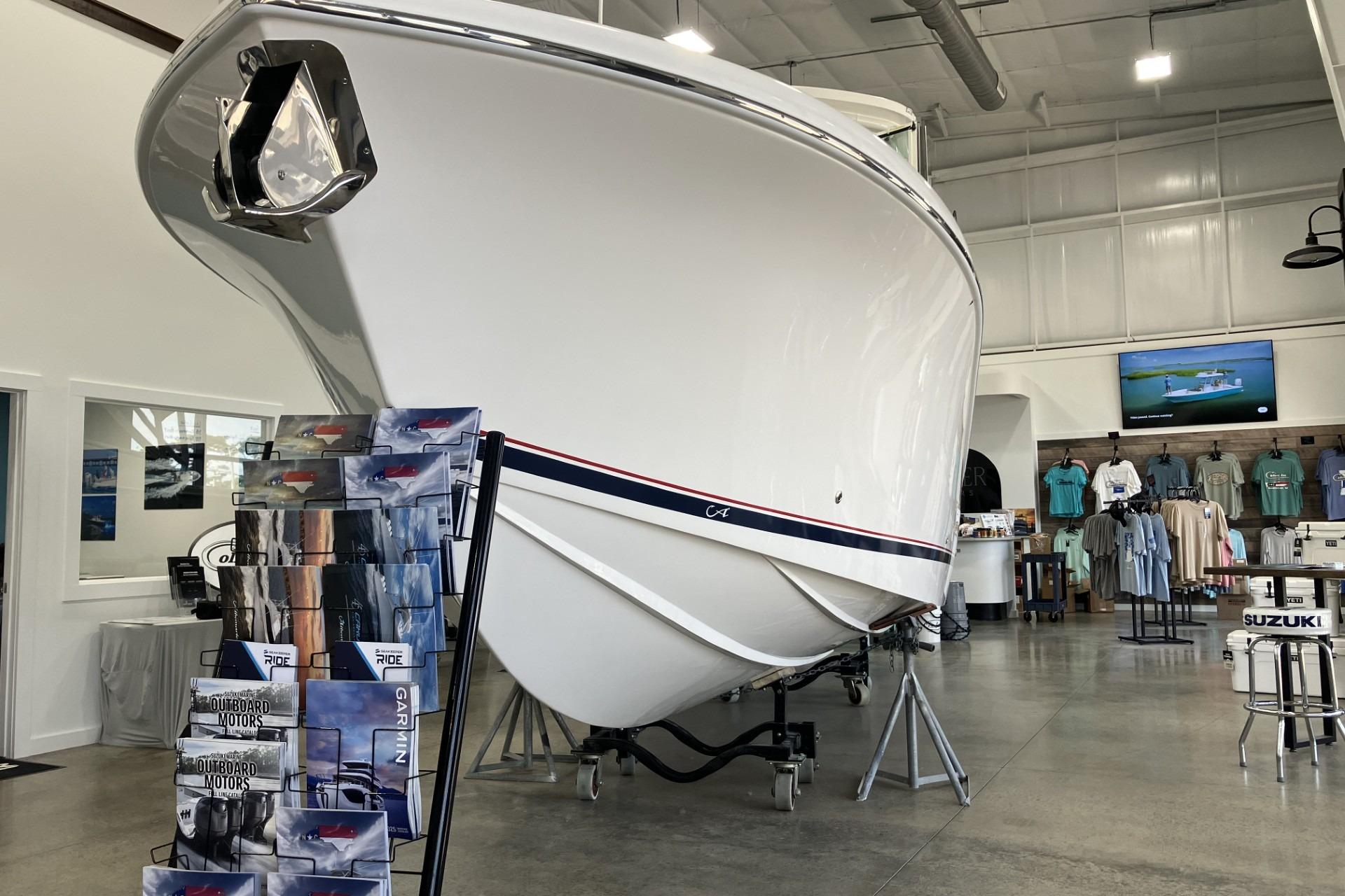 2026 Albemarle 27 Dual Console boat displayed in showroom with merchandise and brochures.