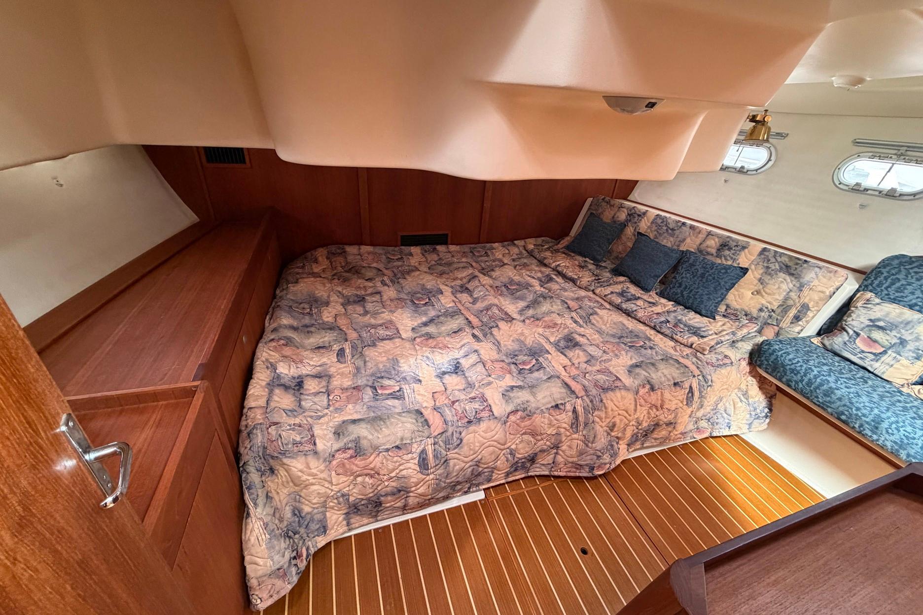 Cozy cabin interior of 1998 Hunter 410 sailboat with patterned bedding and wooden accents.