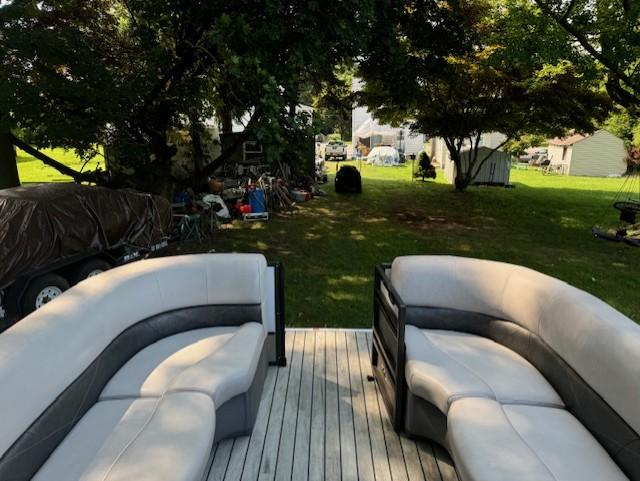 Pontoon boat interior with gray seating, Crest Caribbean 250 L, 2017 model, parked in a grassy yard.