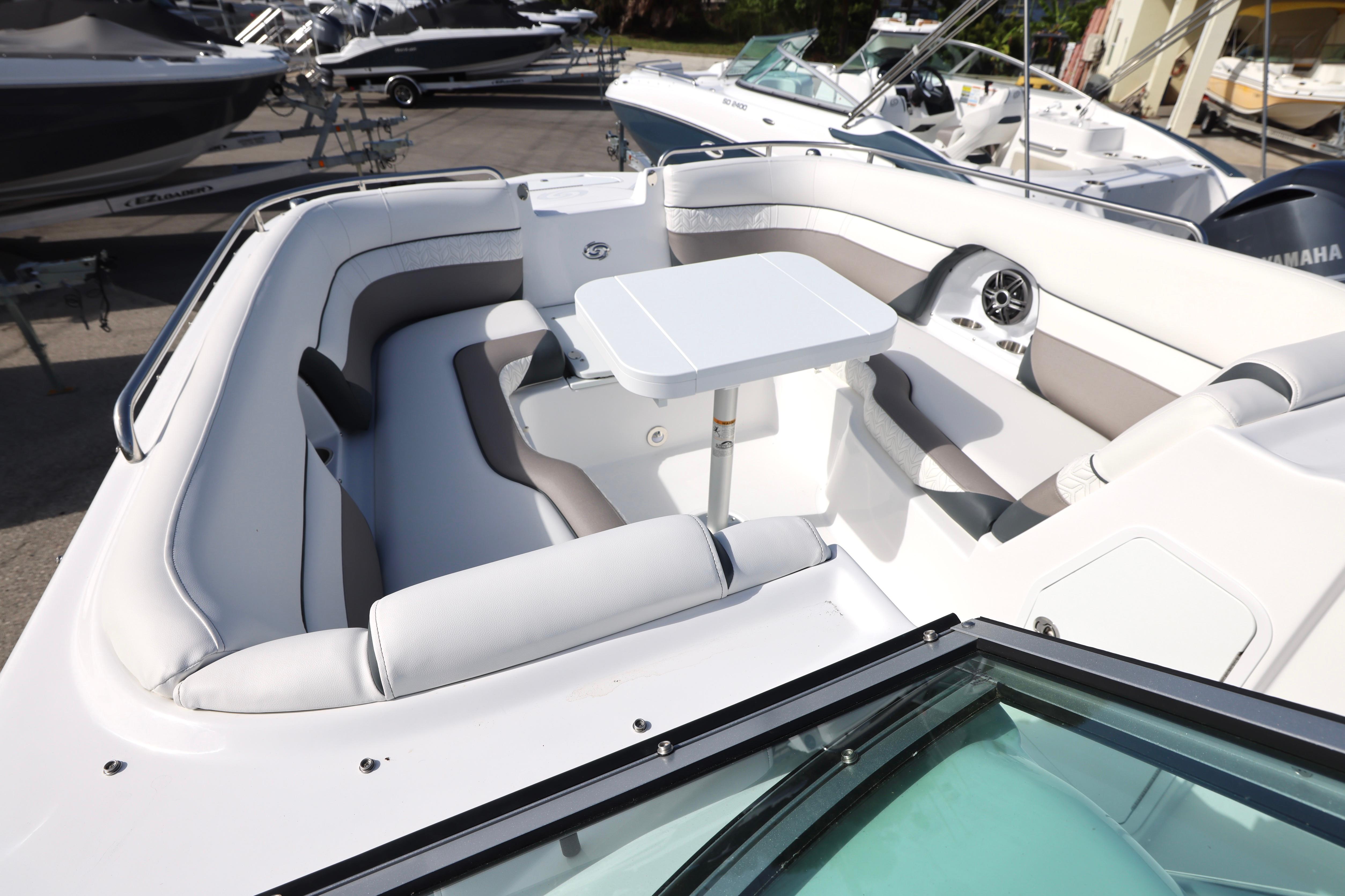 2026 Hurricane SunDeck 2486 OB boat interior with seating and table, docked among other boats.