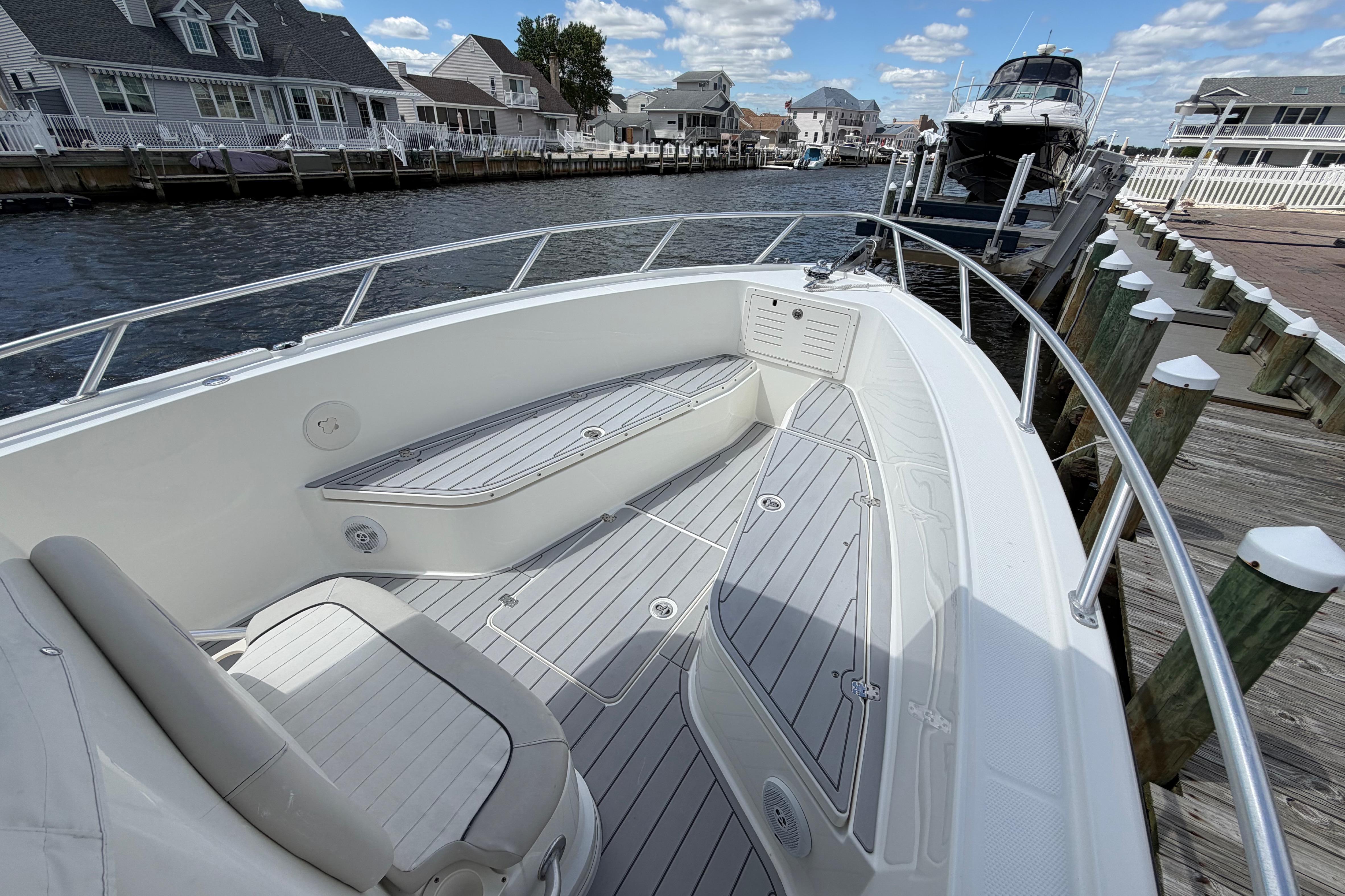 2017 Mako 284 Center Console boat docked by waterfront homes under a blue sky.