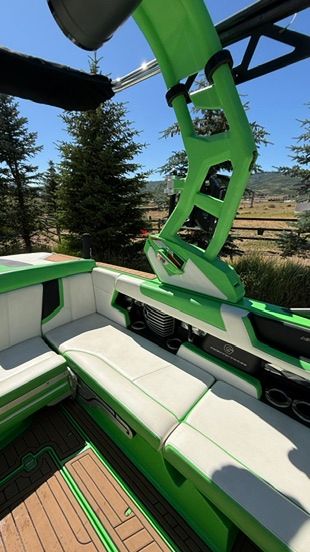 The image shows the interior of a green and white boat with cushioned seats and a tower.