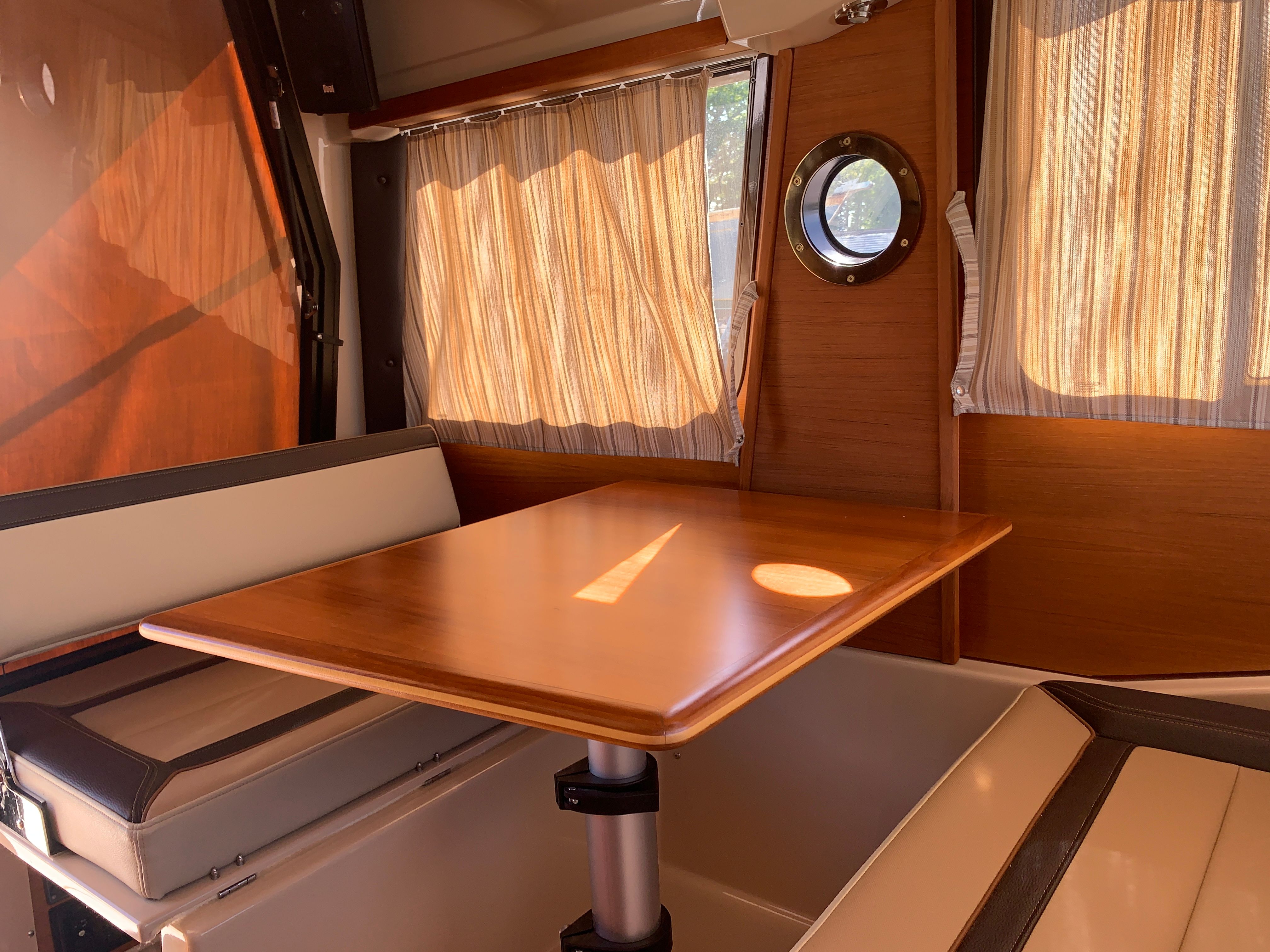 Interior of 2018 Ranger Tugs R-23 yacht with wooden table and seating area.