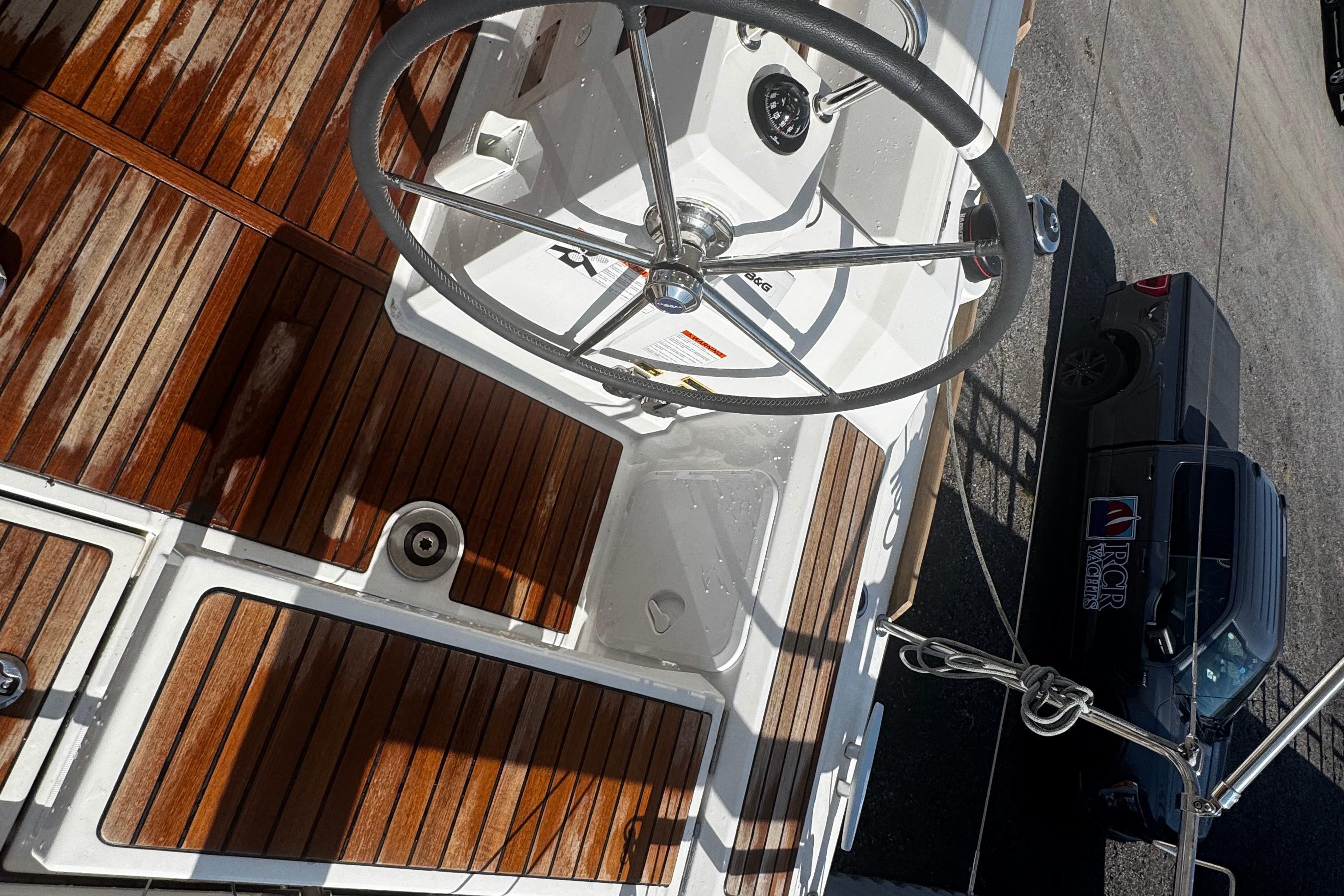 2023 Beneteau Oceanis 38.1 yacht cockpit with wooden deck and steering wheel.