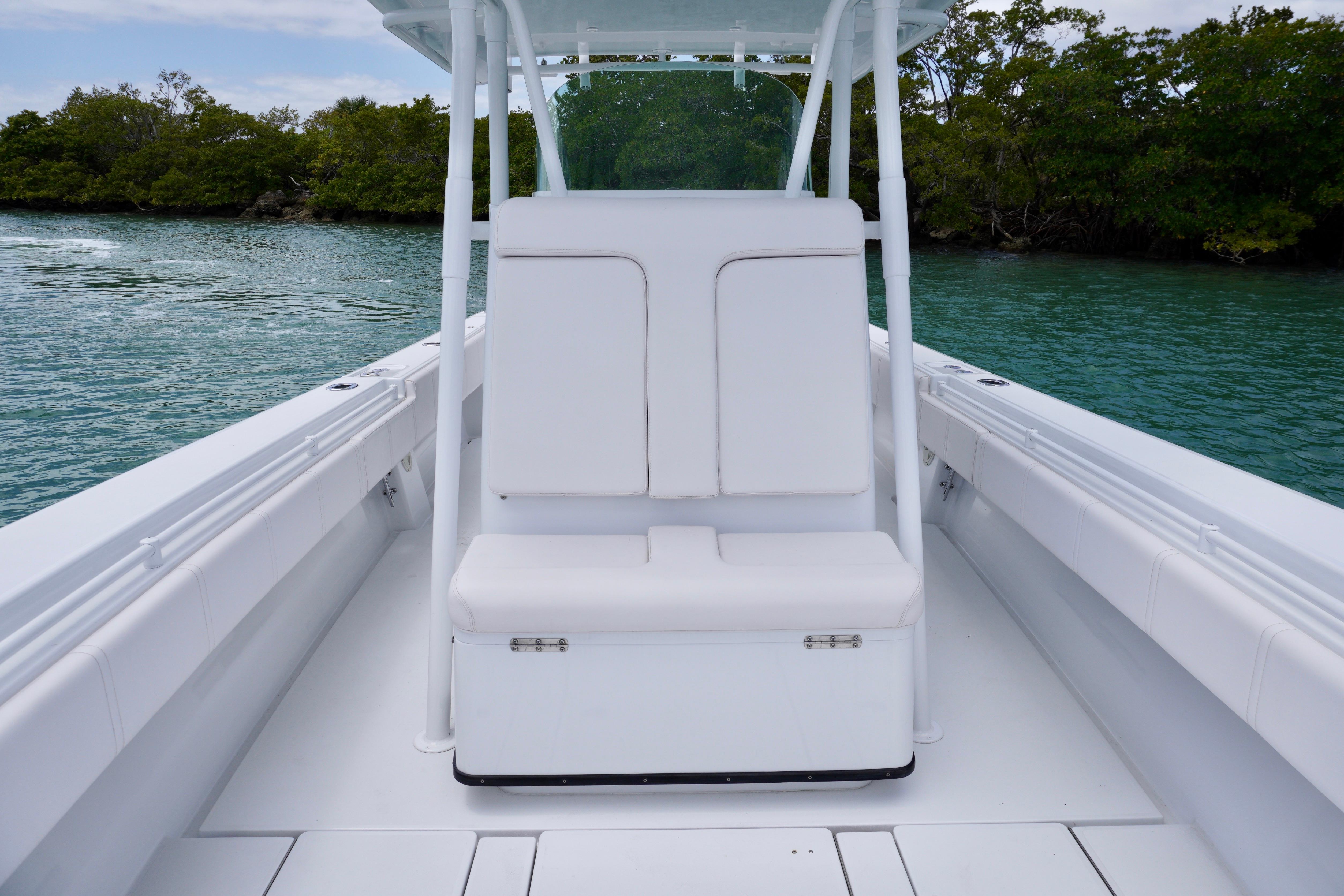 2013 Contender 35 LS boat interior with white seating, calm water, and lush greenery.