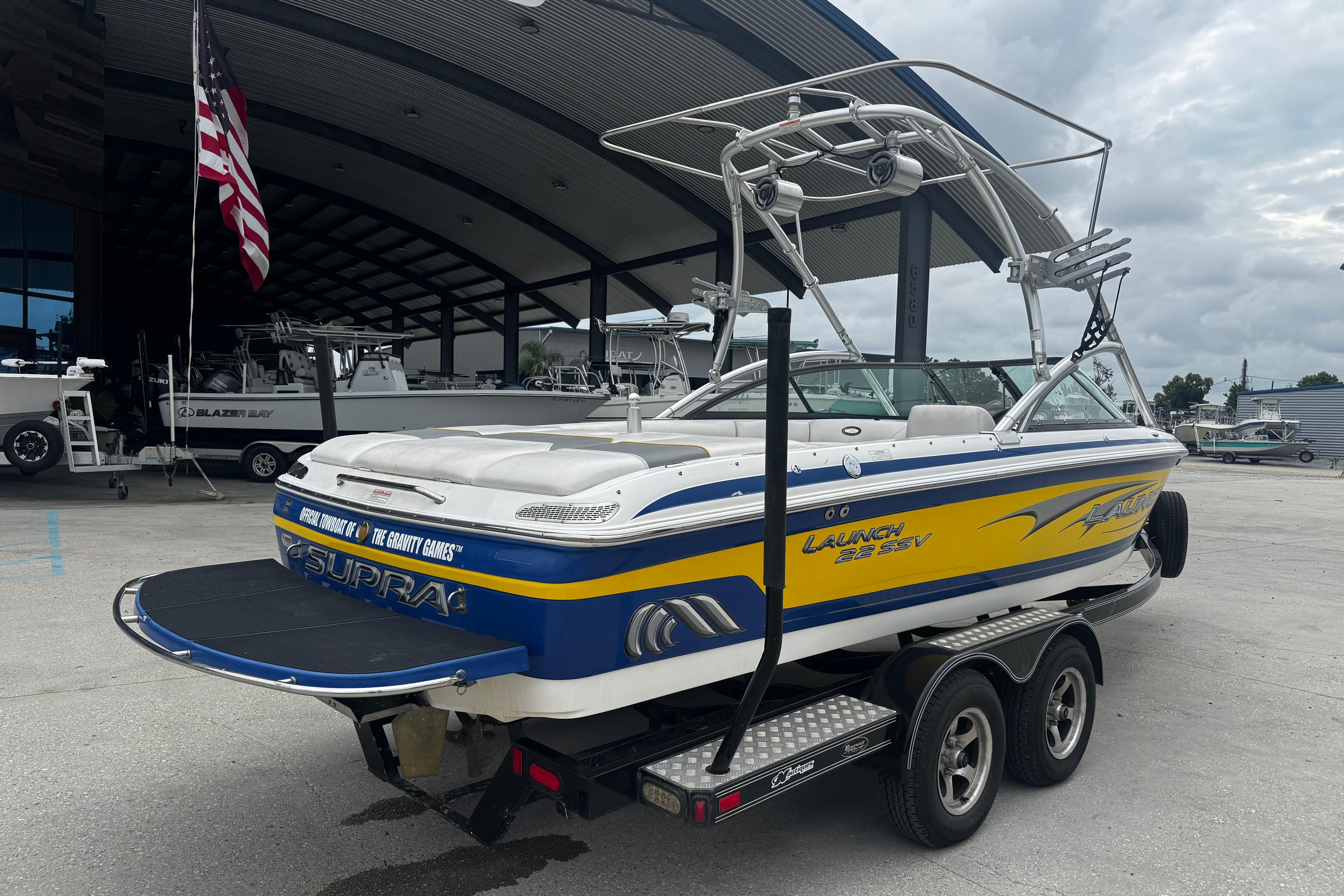 2006 Supra Launch 22 SSV boat on trailer, parked outside a marina.