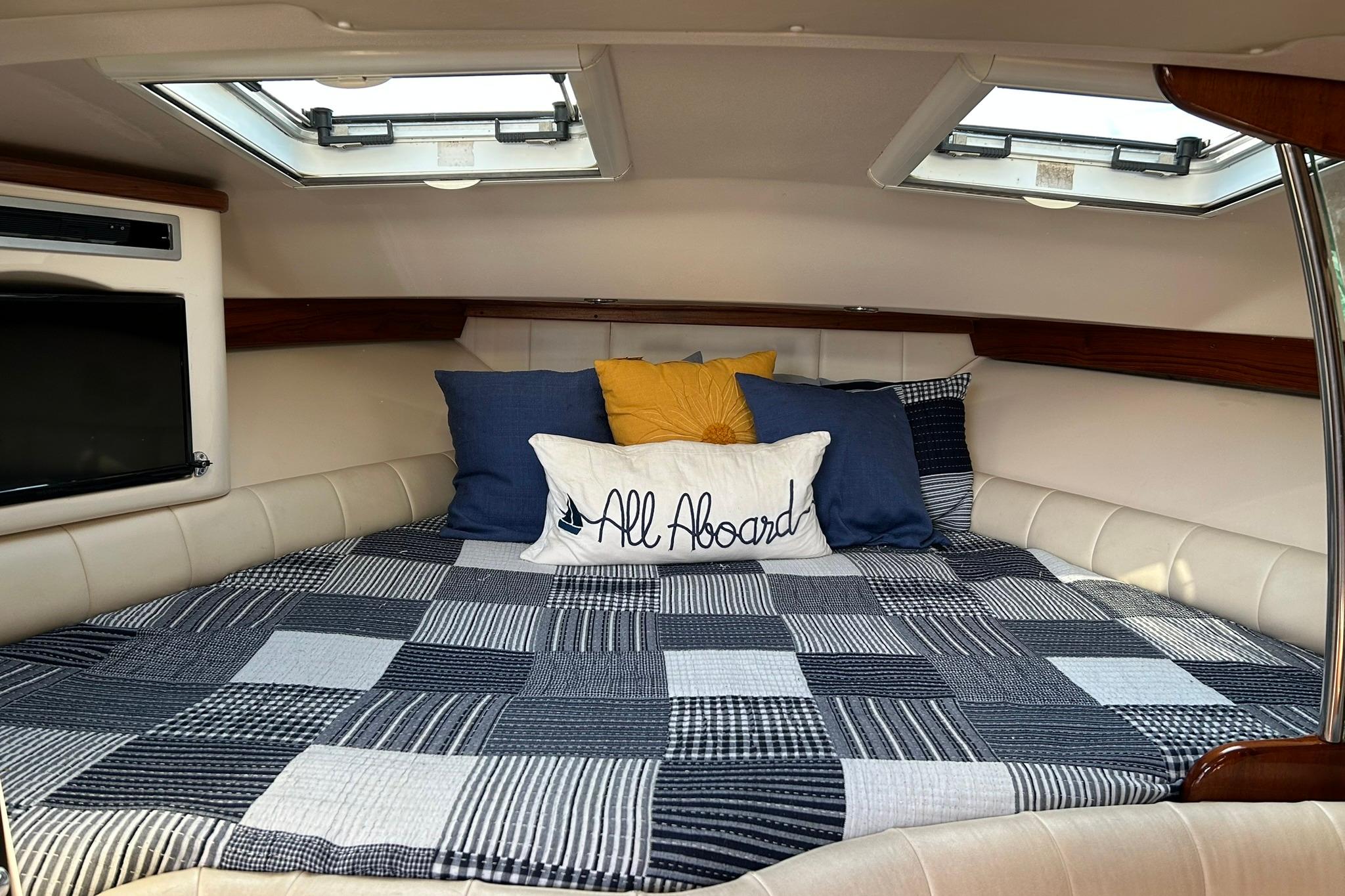 Cozy cabin interior of 2007 Grady-White Express 360 with quilted bedding and decorative pillows.