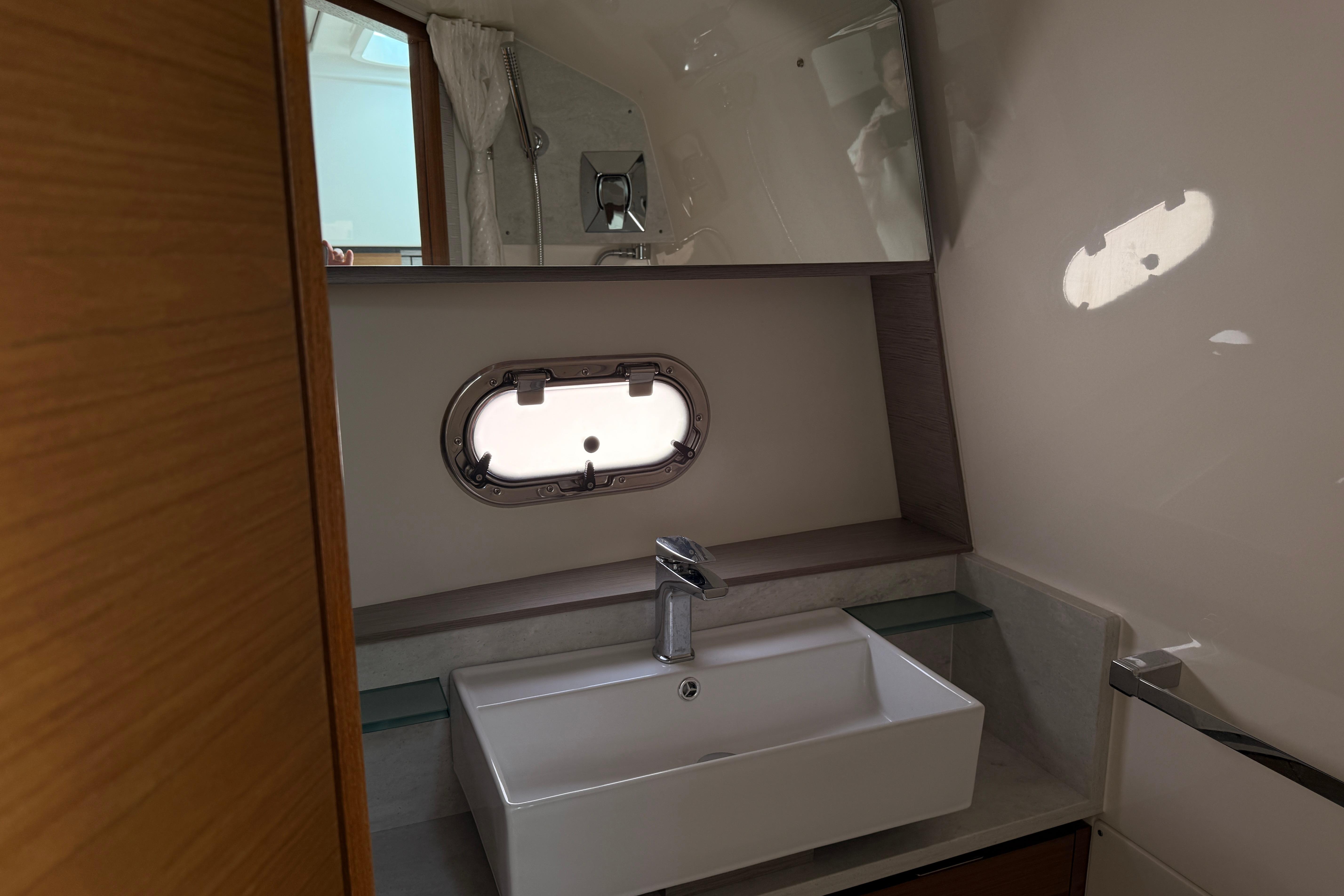 Luxurious bathroom interior of 2022 Tiara Yachts 38 LS with modern sink and porthole window.