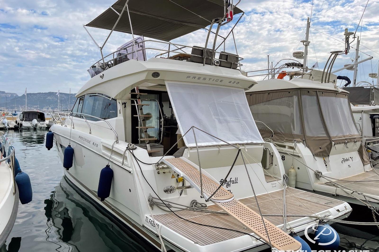Luxury 2016 Prestige 420 yacht docked at marina under cloudy sky.