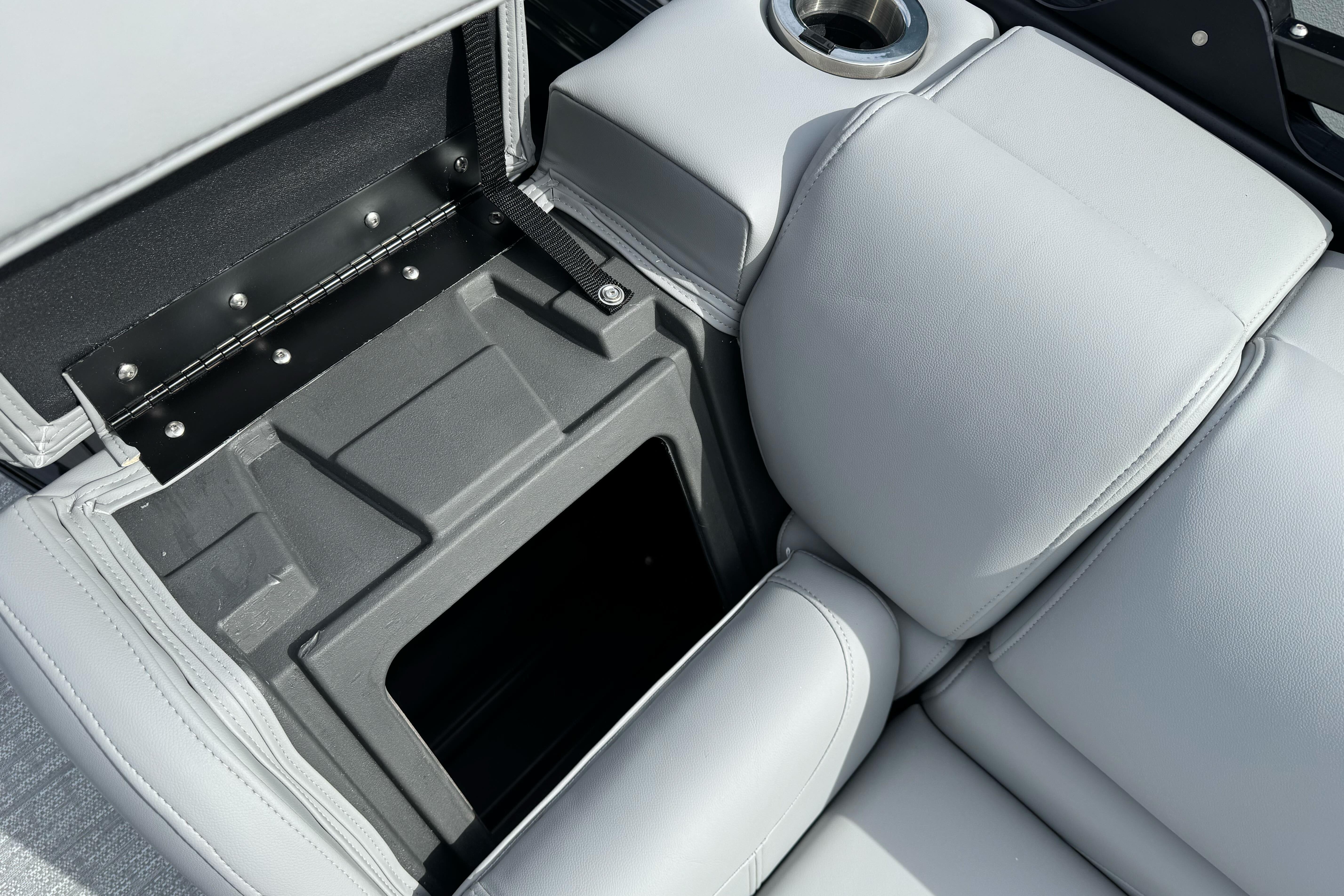 2026 Regency 250 DL boat seat storage compartment with cup holder, featuring sleek gray upholstery.