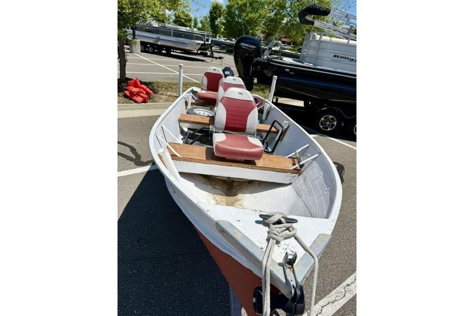 1958 Jon Boat Aluminum model with red seats, parked in a lot under sunny skies.