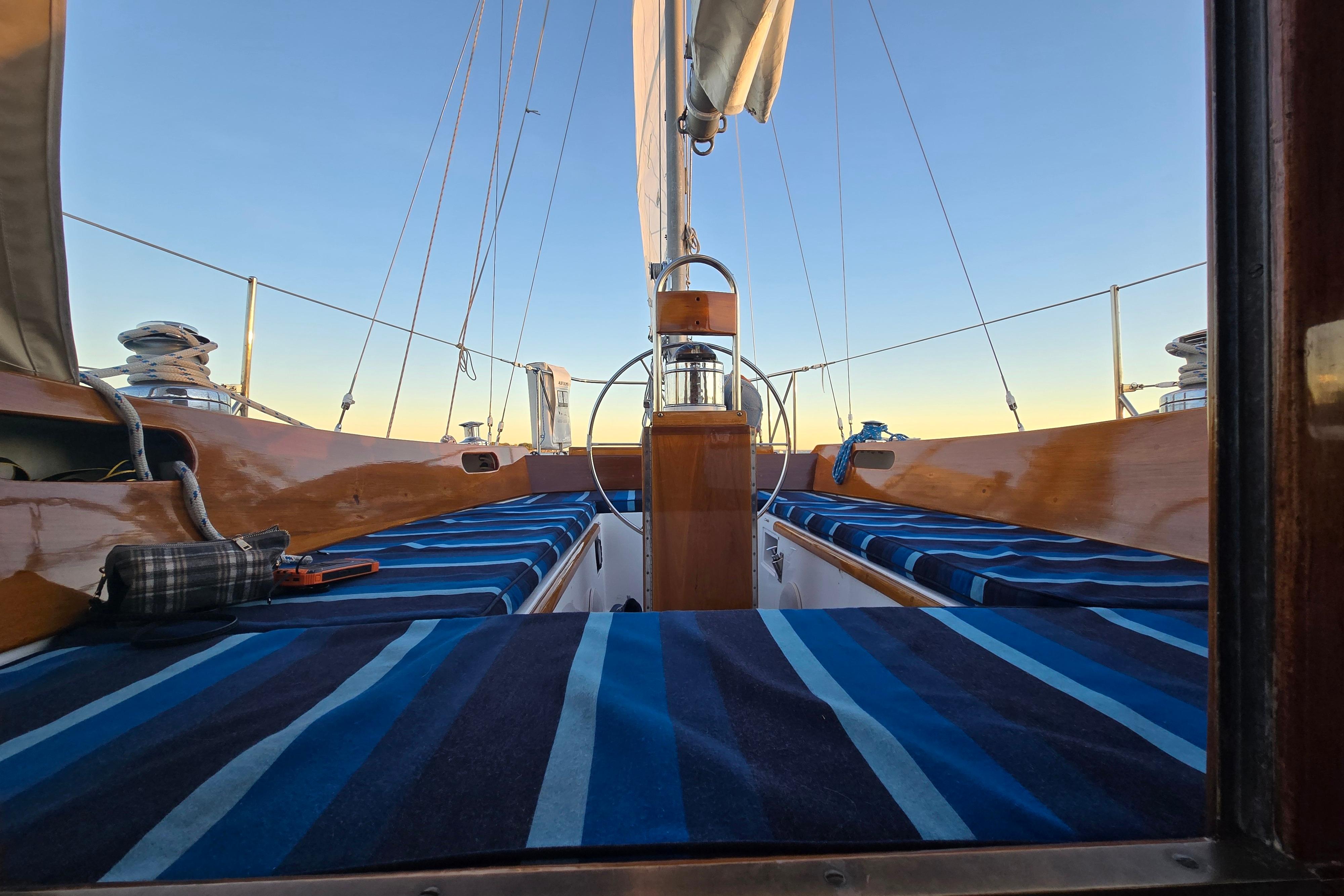 1970 Hinckley Bermuda 40 sailboat interior with striped cushions and wooden details at sunset.