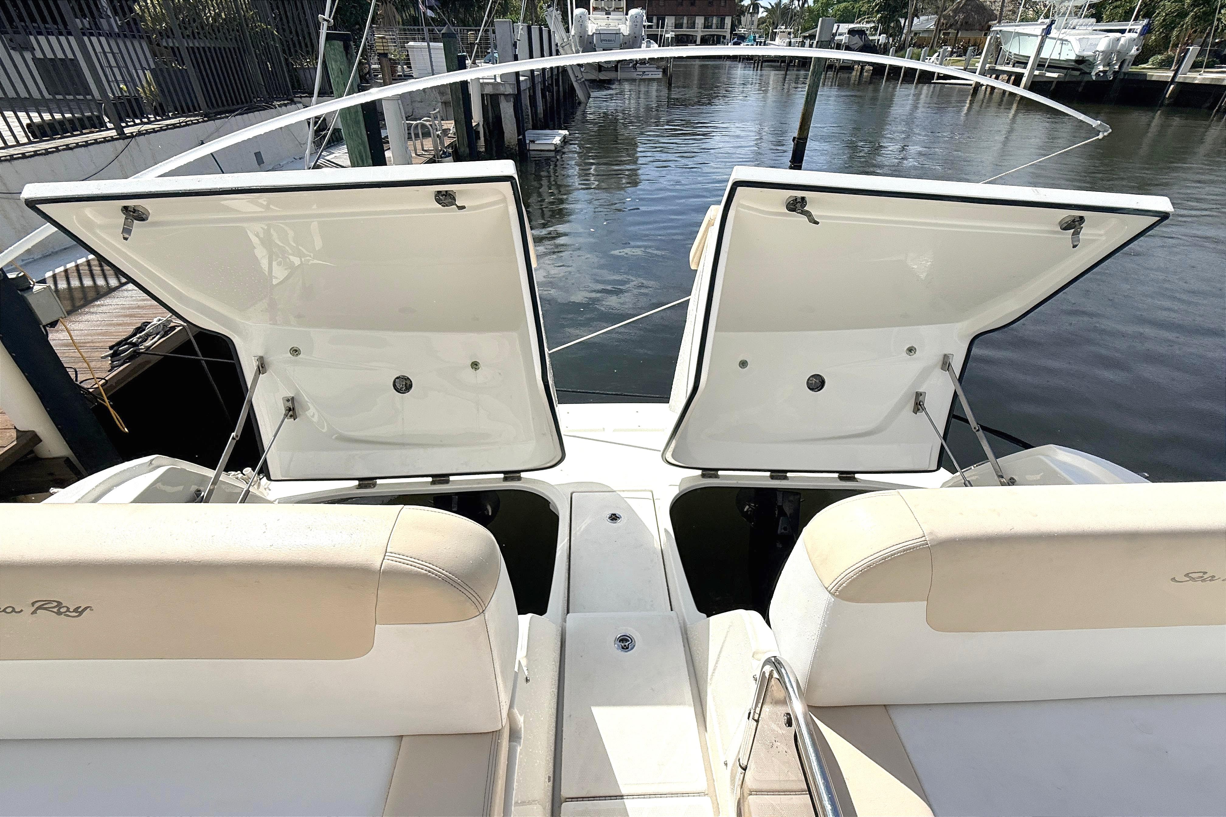 2013 Sea Ray 370 Venture boat with open storage compartments, docked by the water.